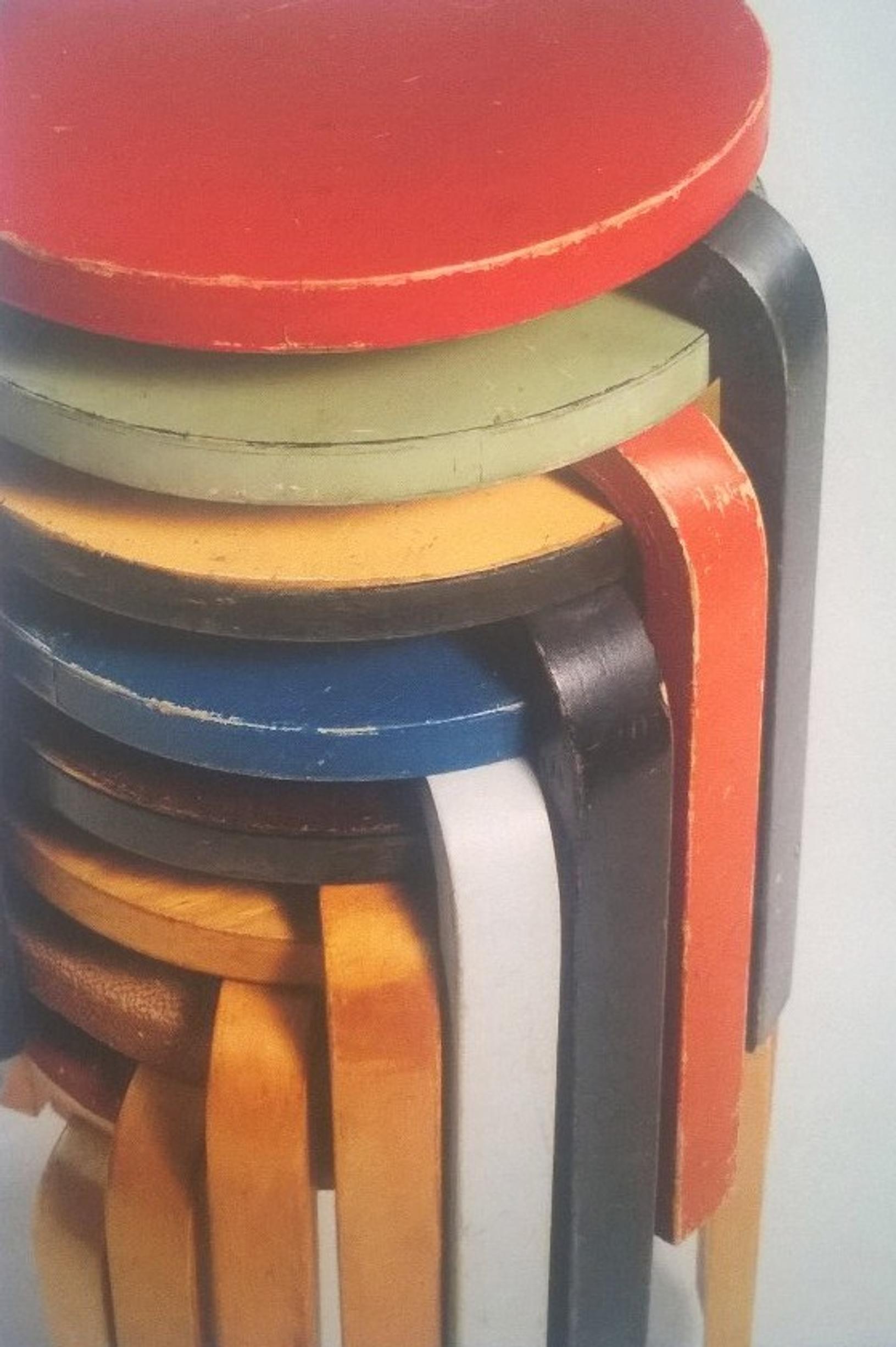 erivärisiä Artekin jakkaroita pinossa