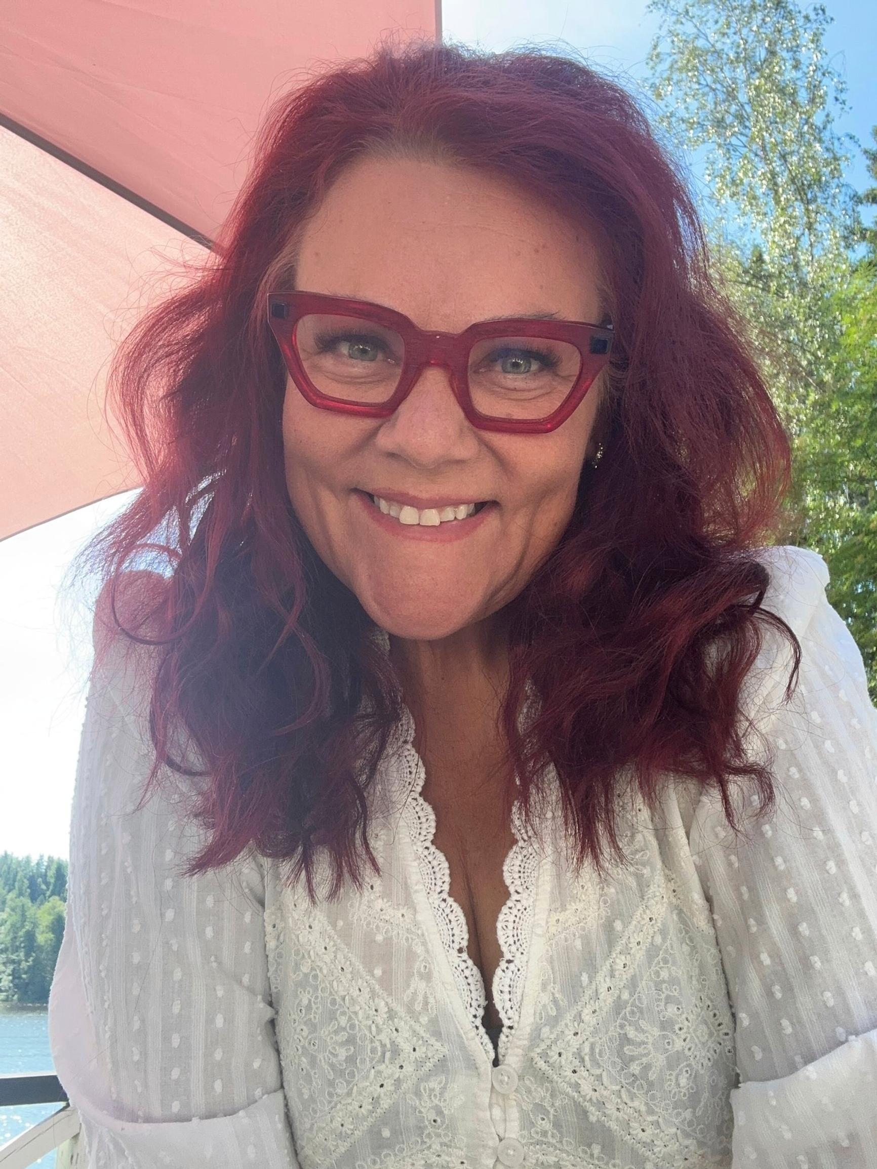 Supernanny Pia Penttala hymyilee aurinkovarjon alla