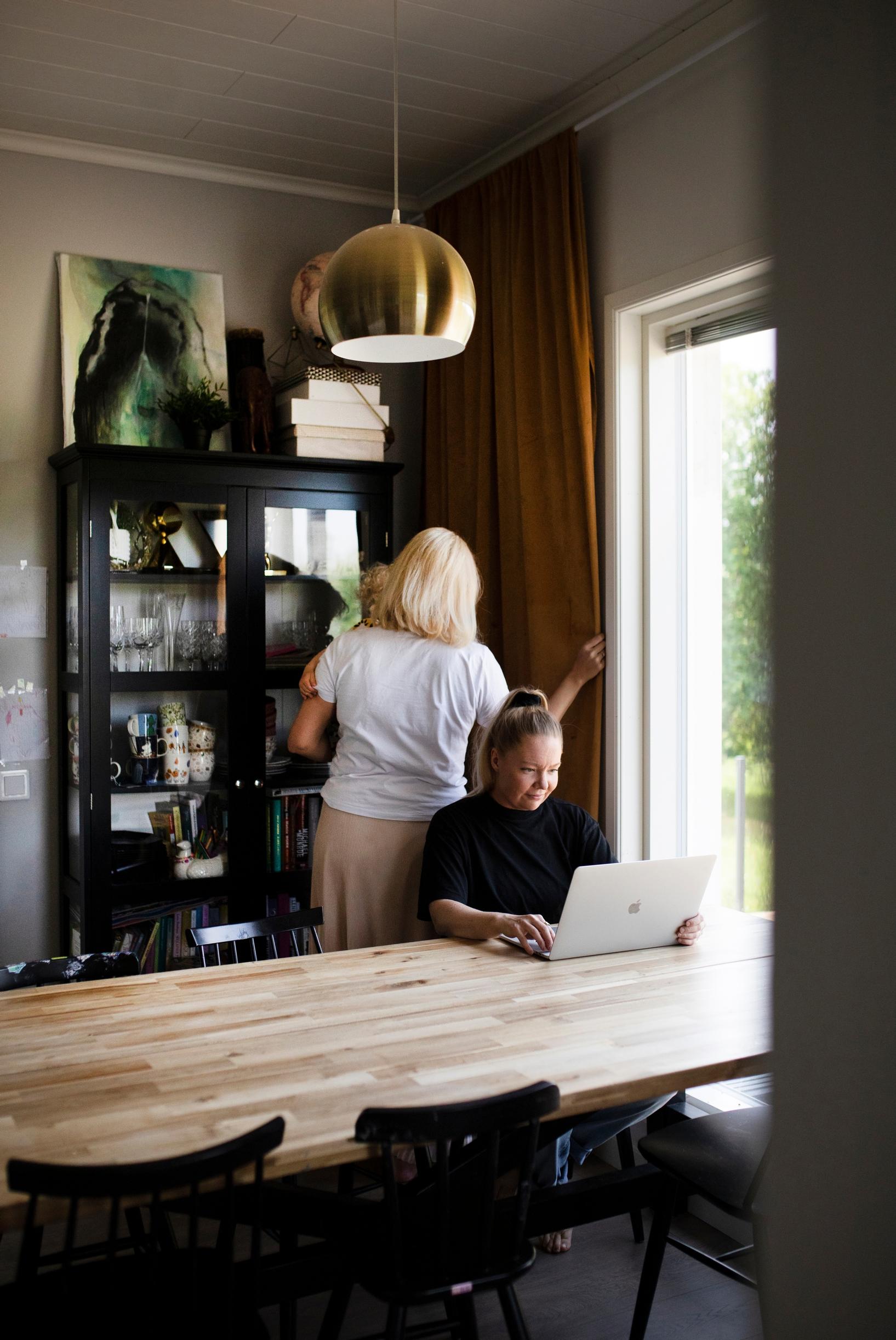 nainen istuu tietokoneella pöydän ääressä