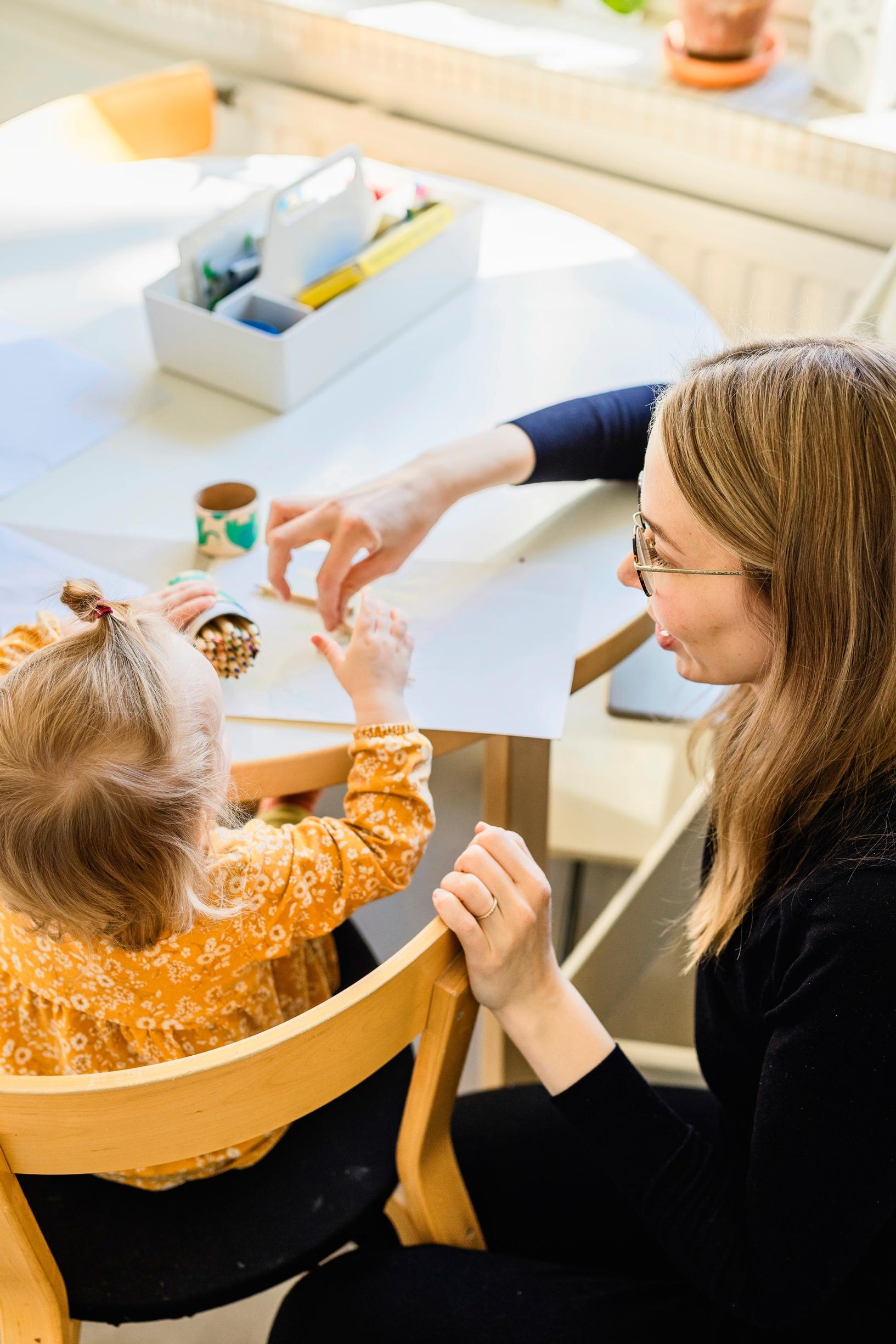 Äiti ja lapsi ruokapöydän ääressä piirtämässä