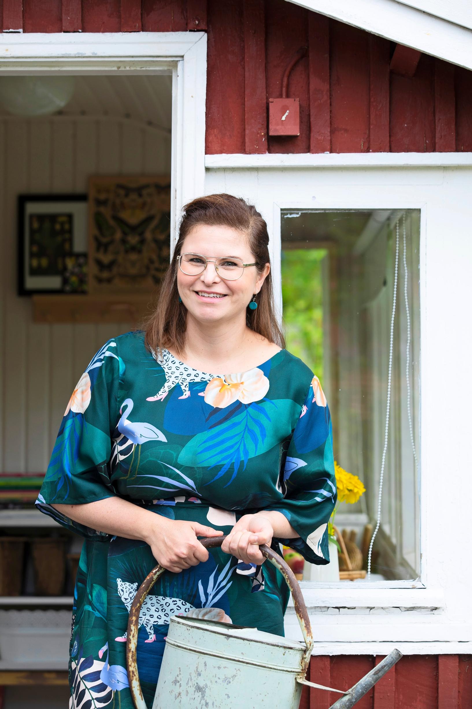 Nainen kuistilla kastelukannu kädessään
