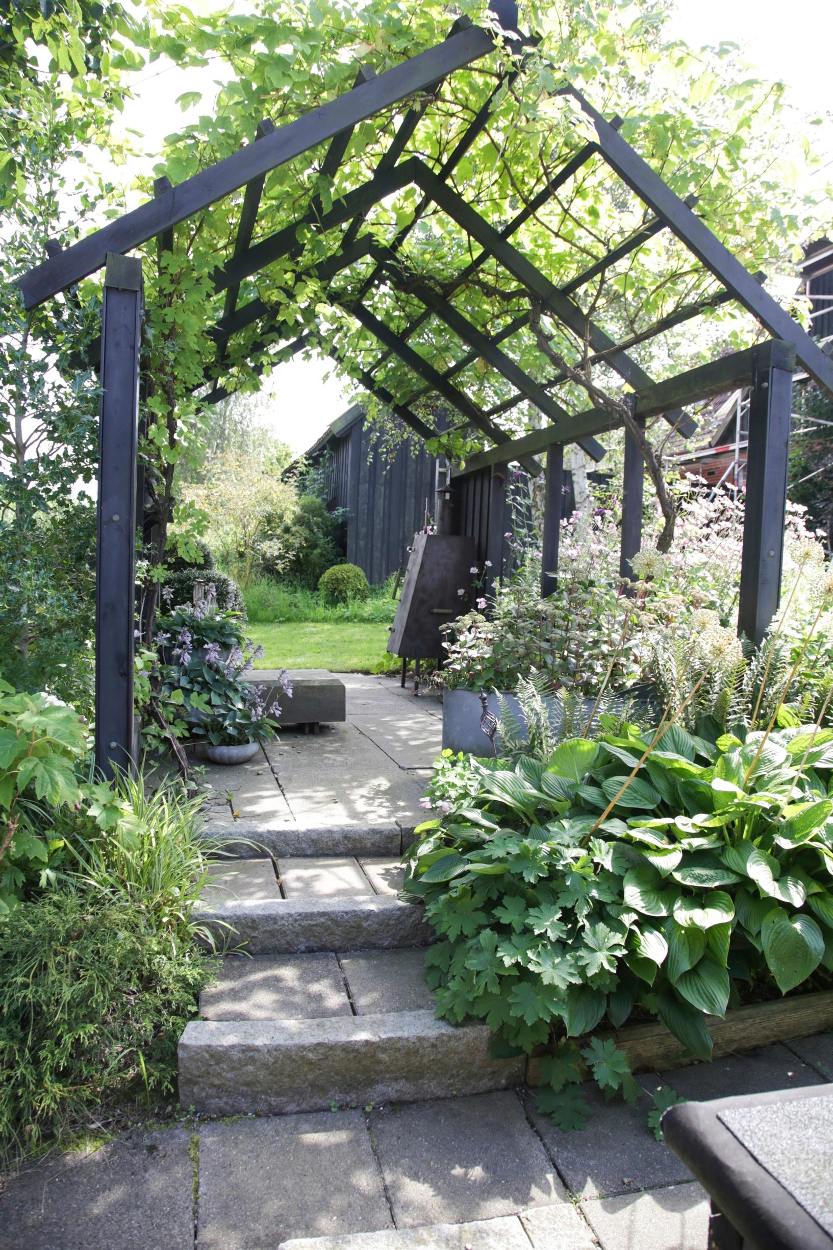harjakattoinen, mustaksi maalattu pergola.