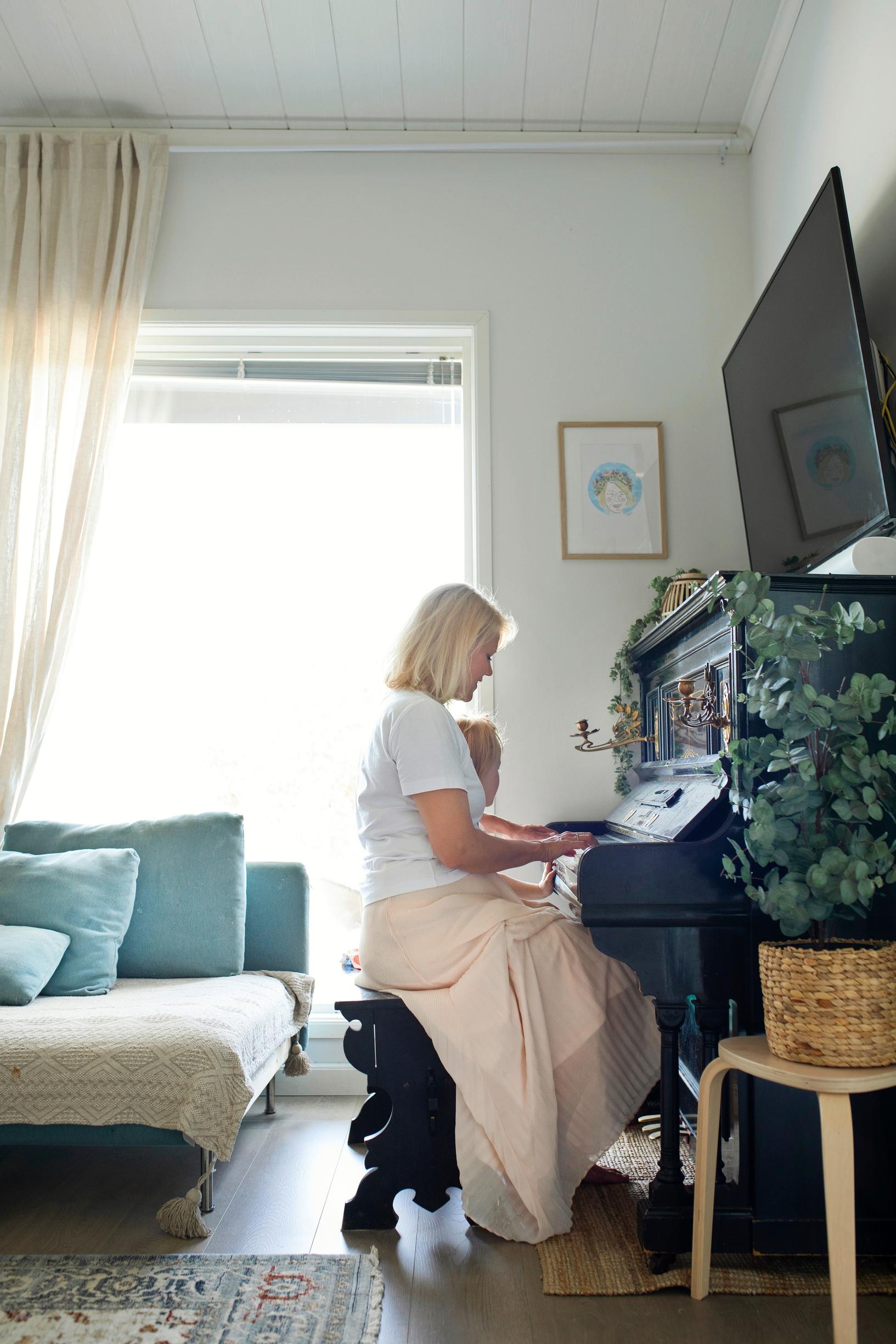 nainen soittaa pianoa olohuoneessa