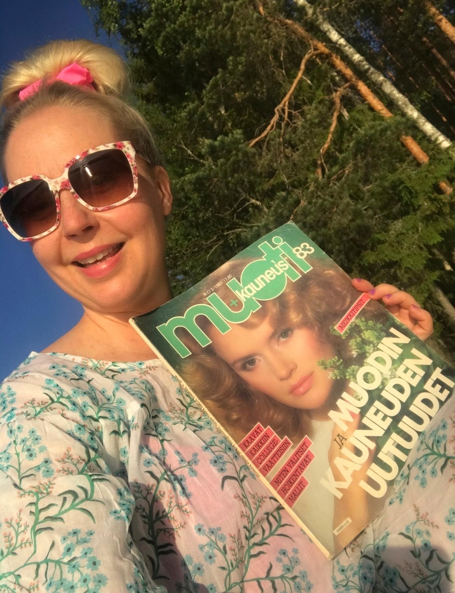 Krisse Salminen aurinkolasit päässä ja vanha naistenlehti kädessä