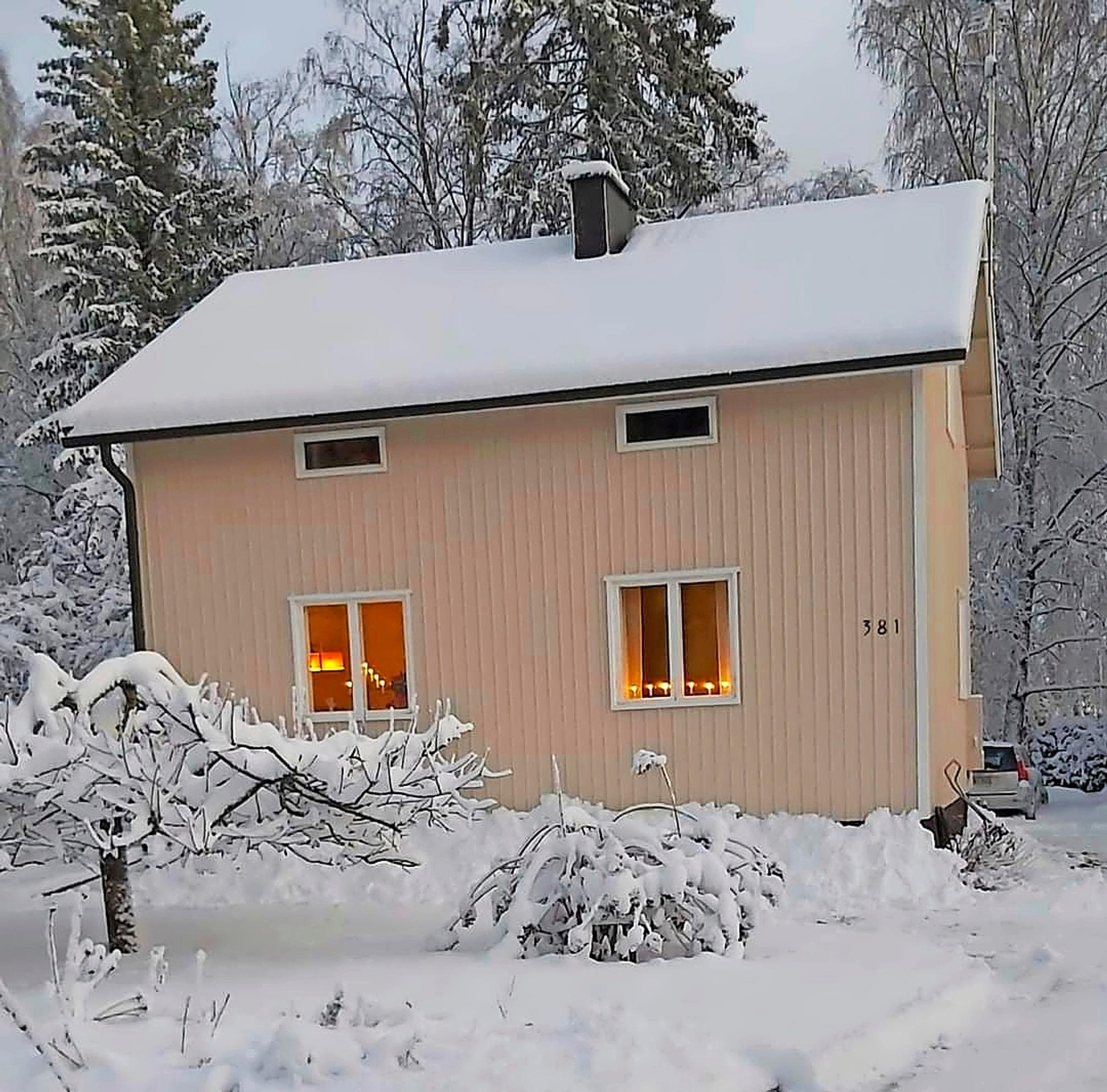 vaalea mummonmökki ja lumisia puita