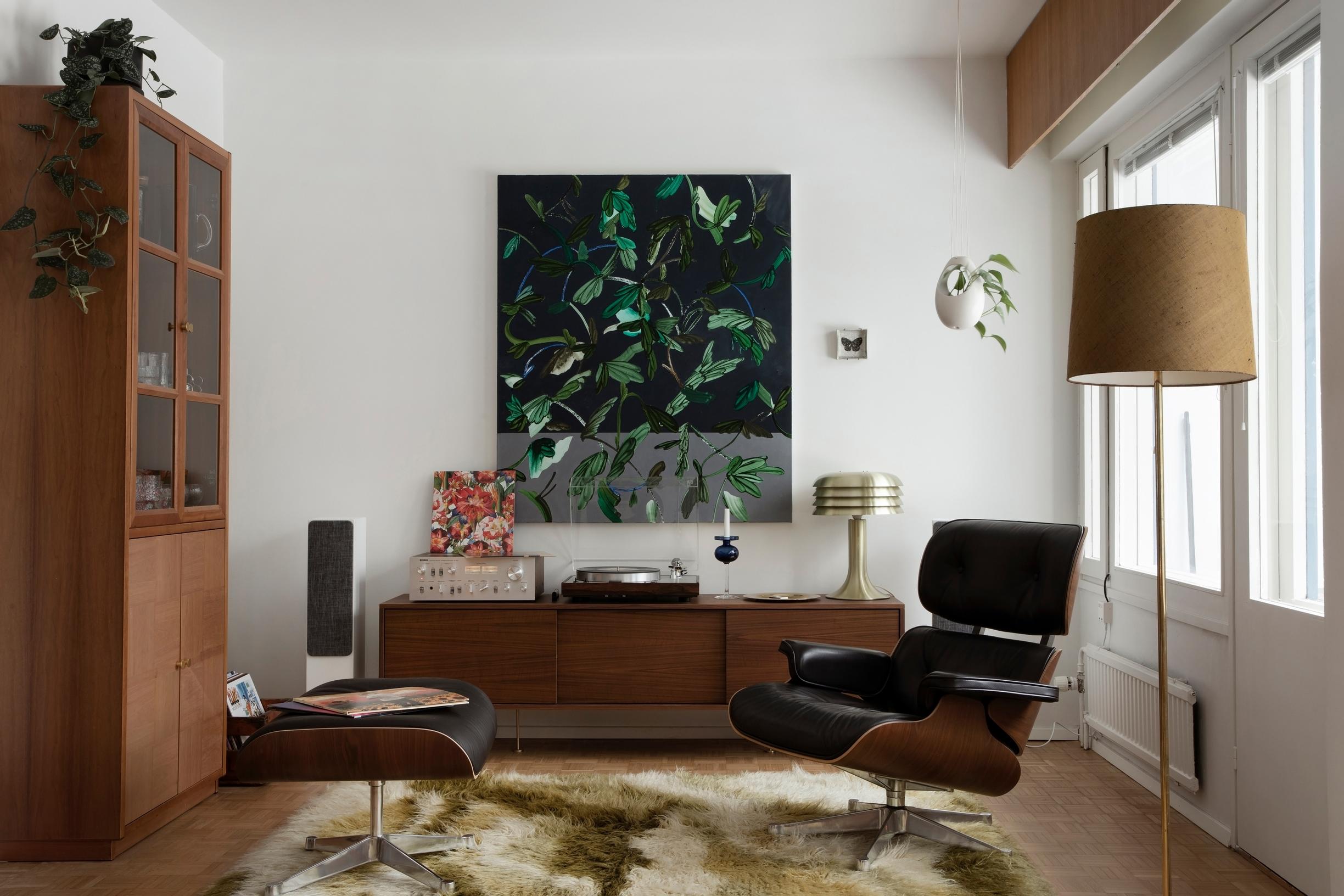 Vitran Eames Lounge -nojatuoli ja suuri tummanvihreäsävyinen maalaus matalan senkin yllä