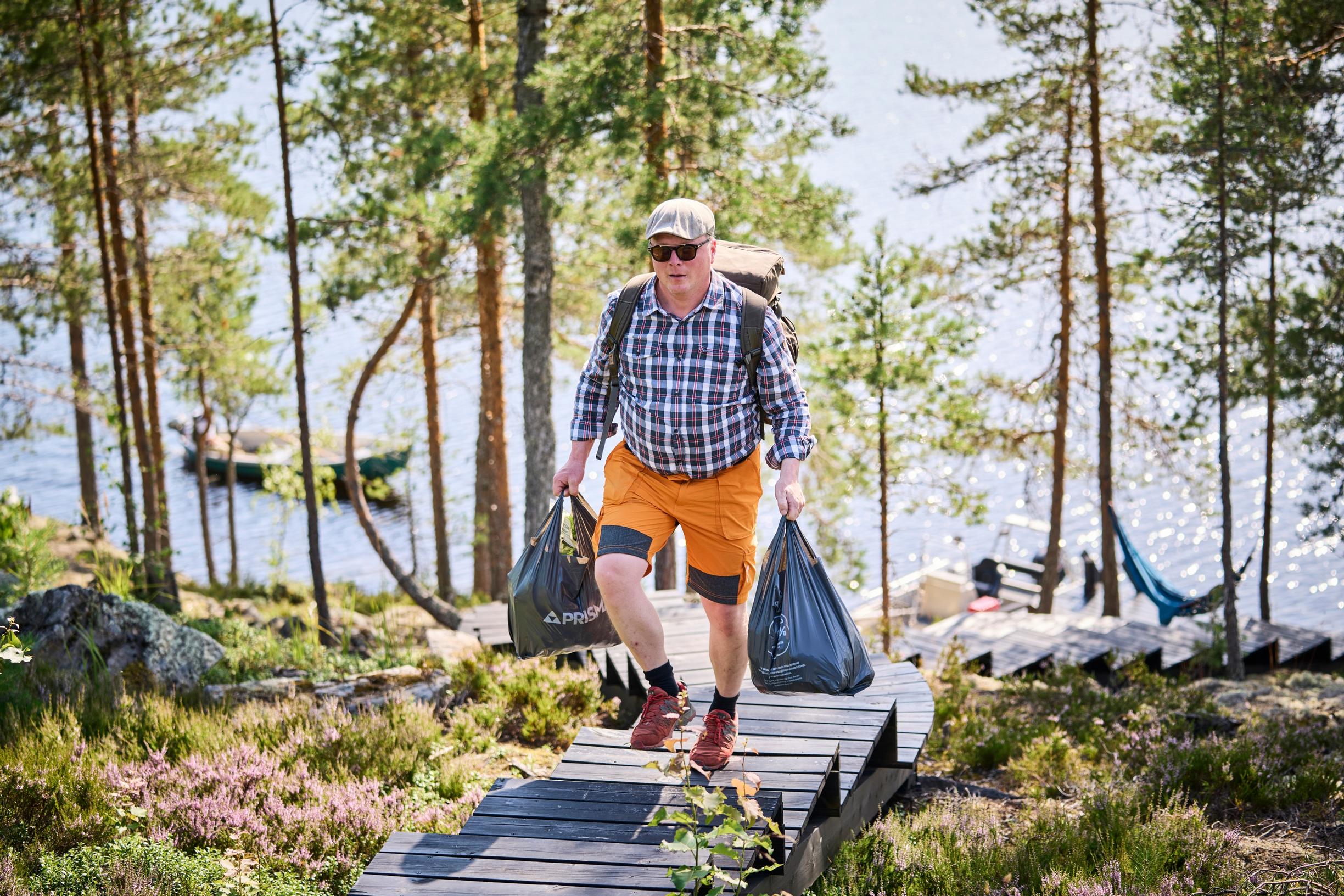 Mies kantaa kauppakasseja portaita ylös rannasta