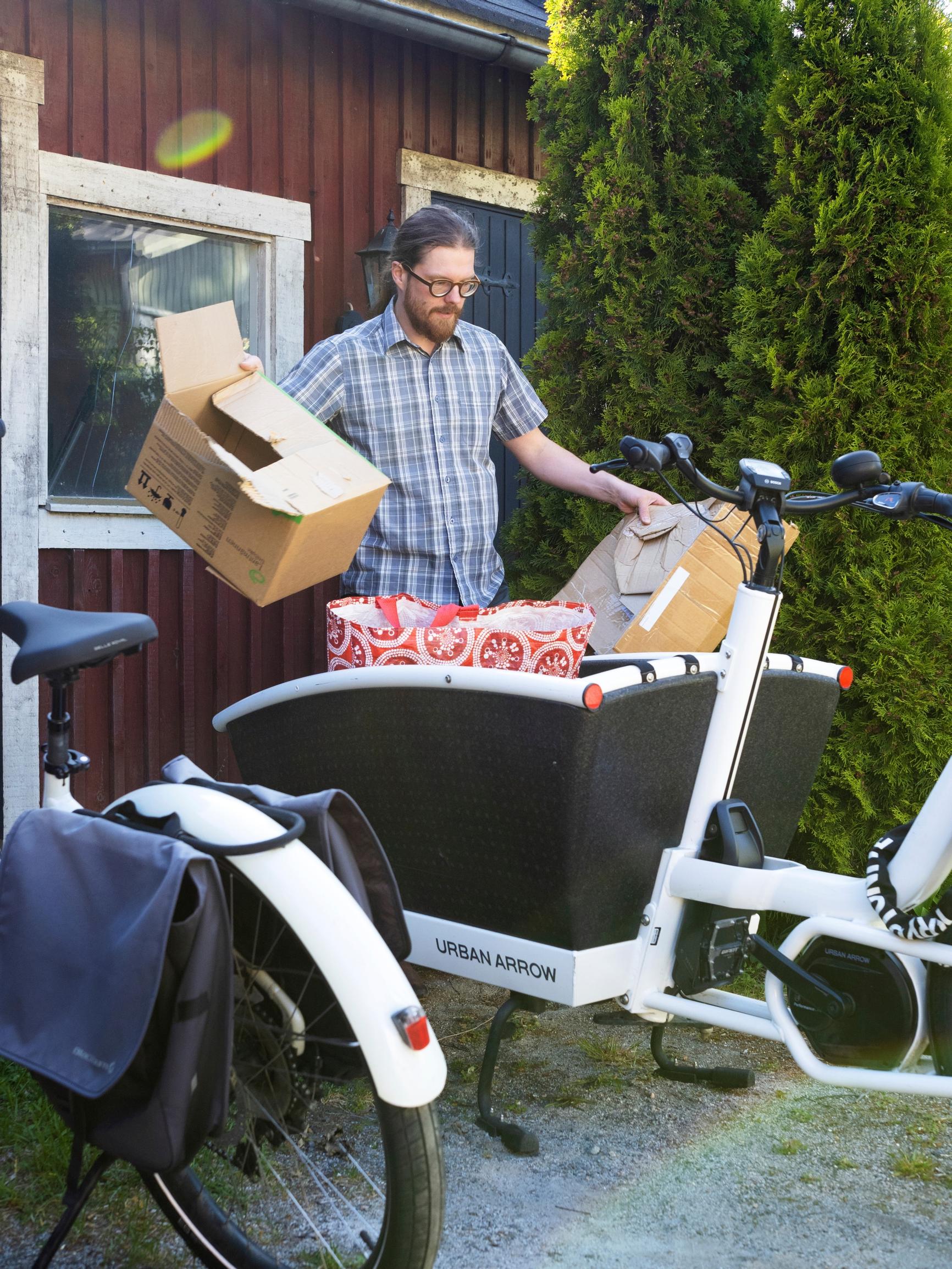 mies pakkaa laatikoita kuormapyörän kyytiin