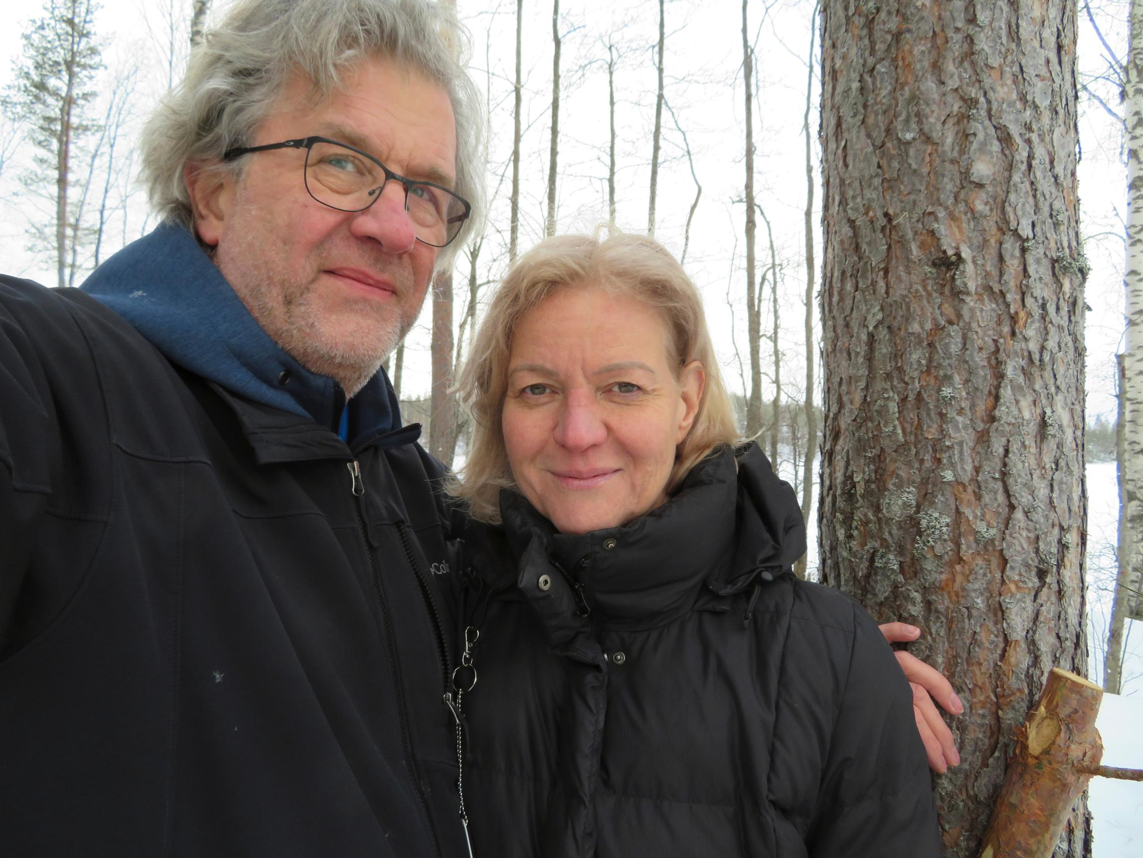 Cati Sundström Jyrki Hyytiäisen kainalossa ison männyn edessä järvimaisemassa