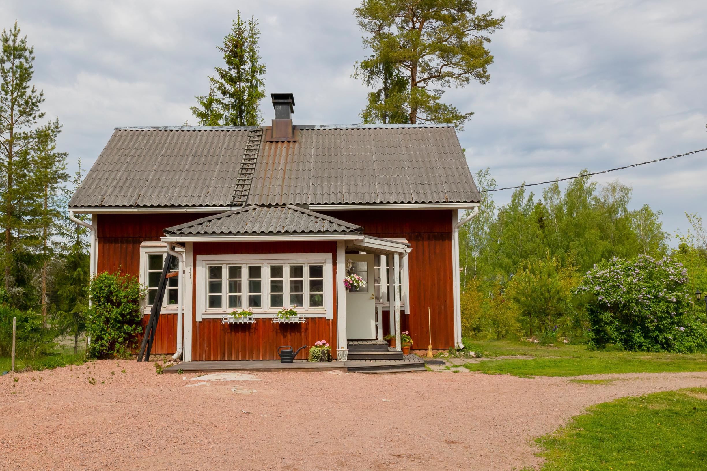 Punainen puutalo maalaismaisemassa