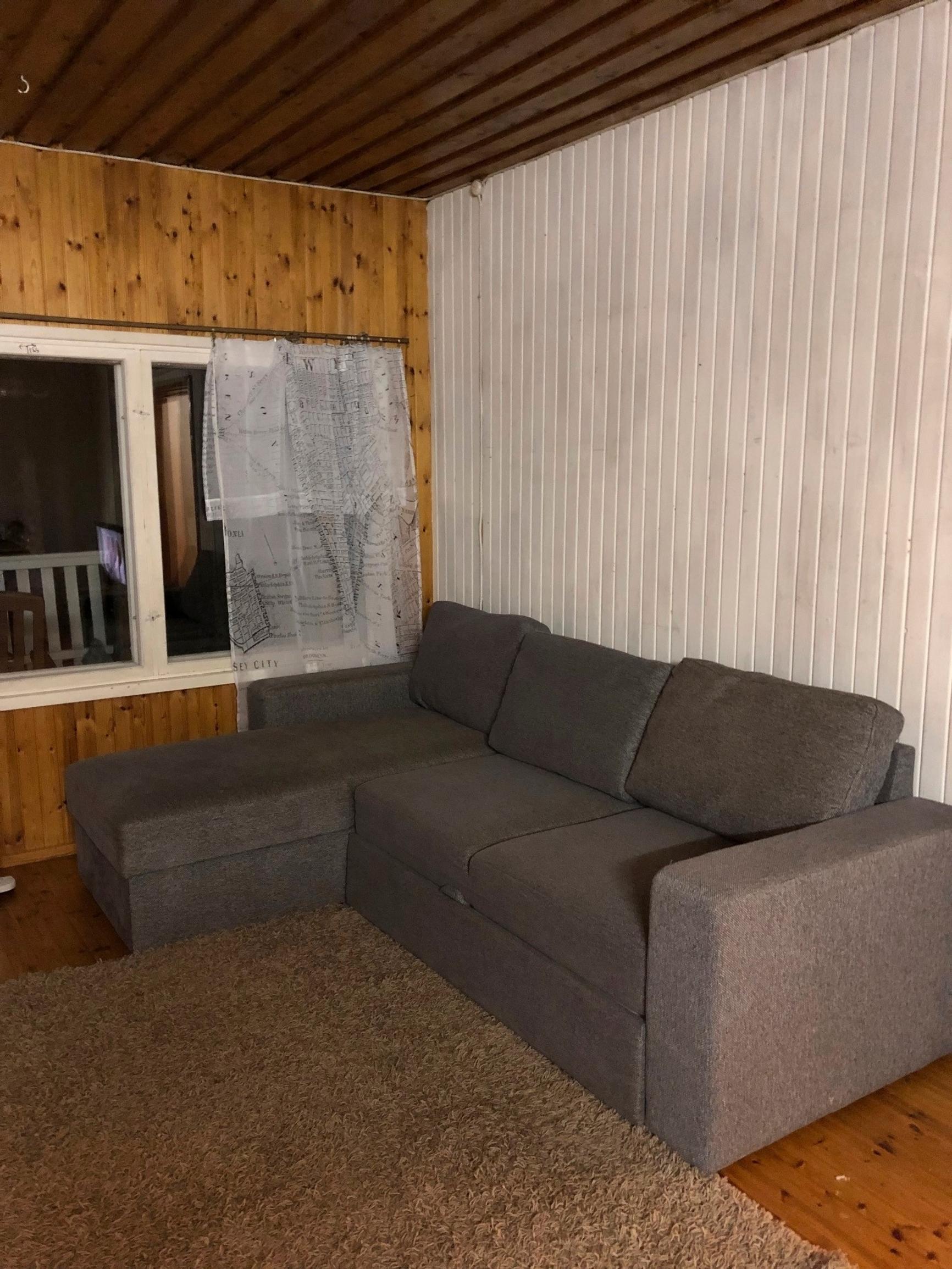 tumma kulmasohva, iso matto ja erivärisiä seiniä