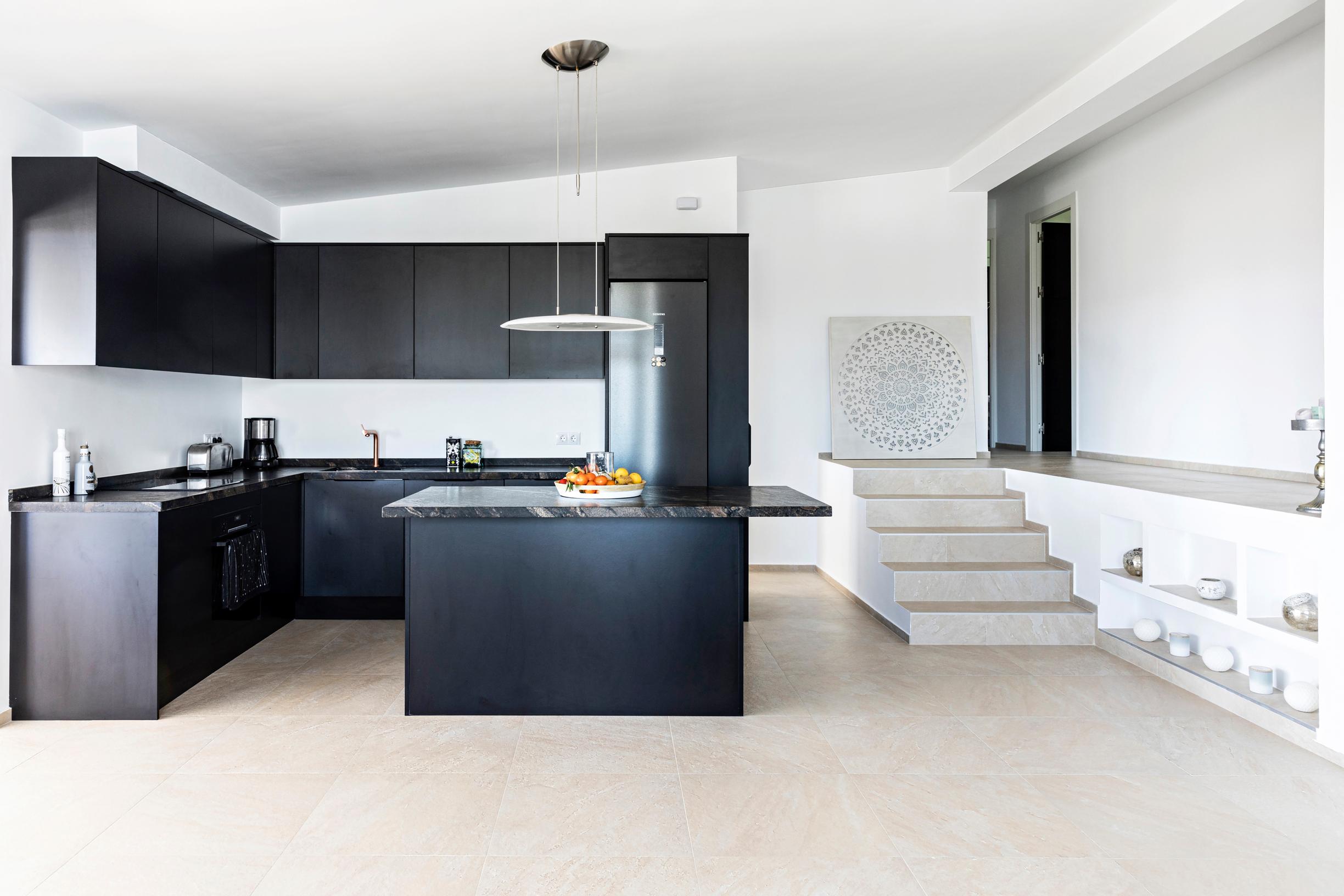 Avokeittiön mustat kaapit tuovat syvyyttä vaaleaan tilaan