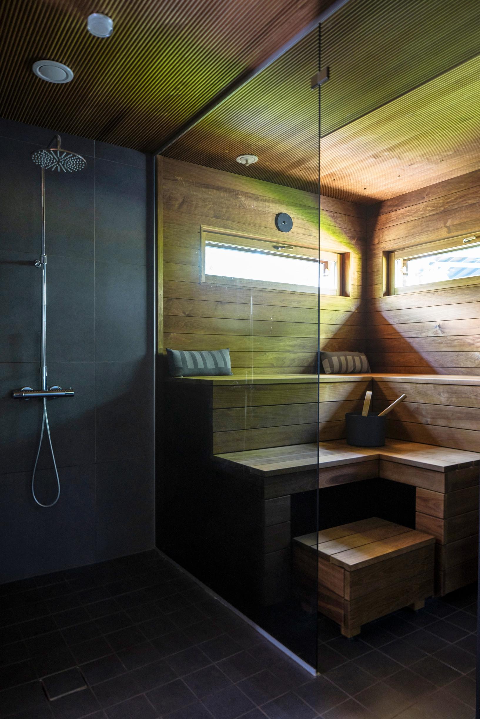 Lasiseinäinen sauna ja tumma suihkutila