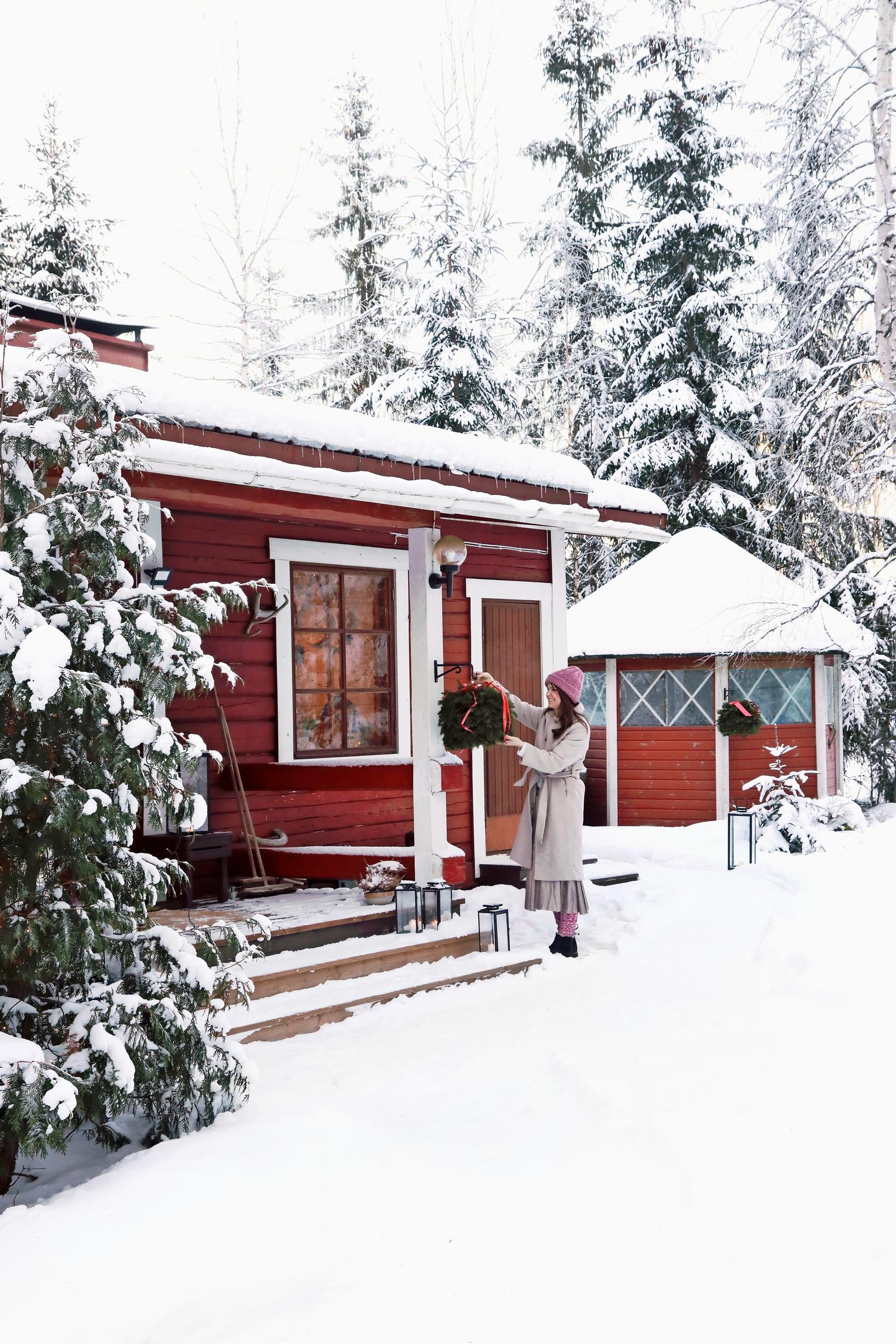 Ulla Parviainen lumisen mökin pihalla Pusulassa