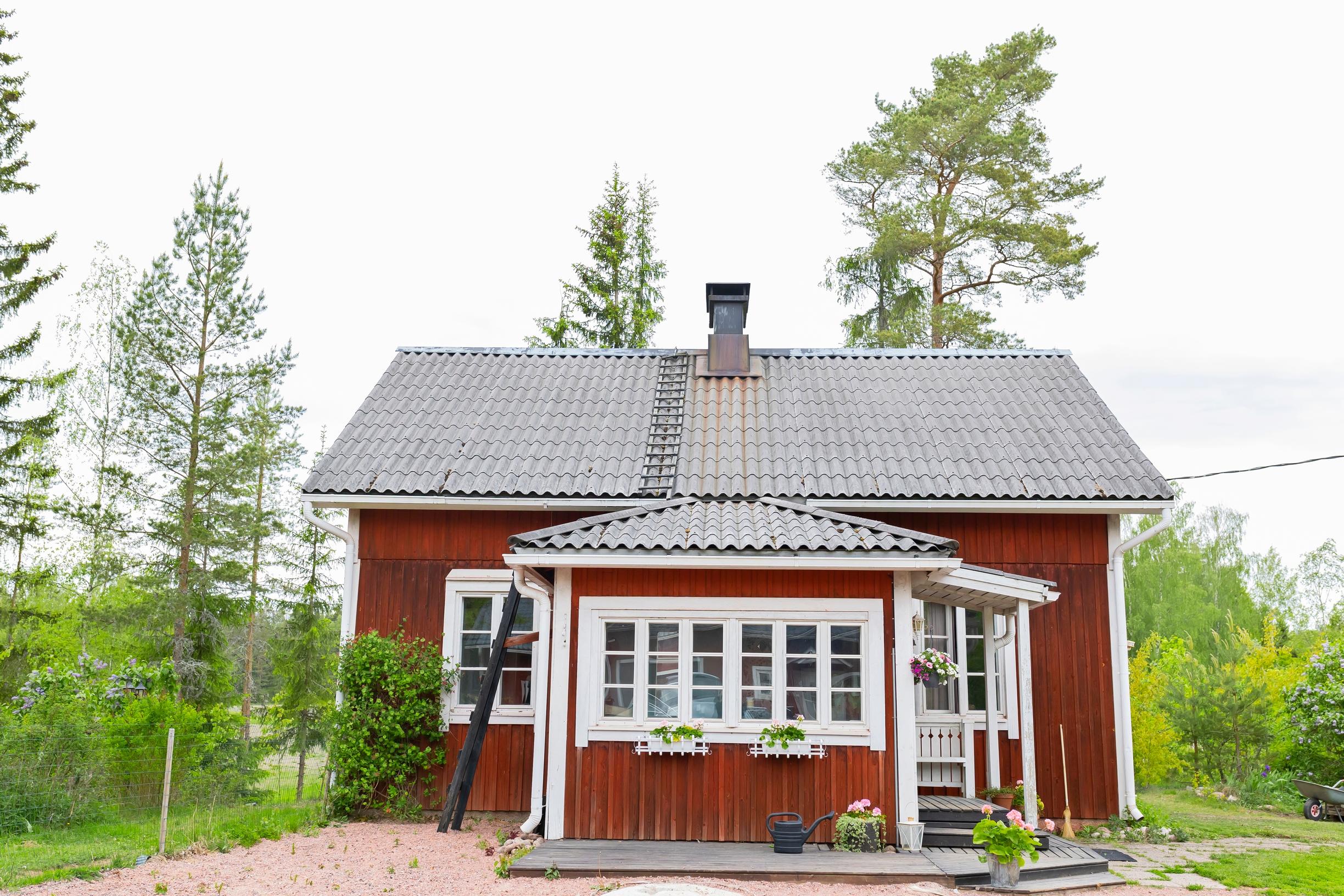 Punainen puutalo metsän laidalla