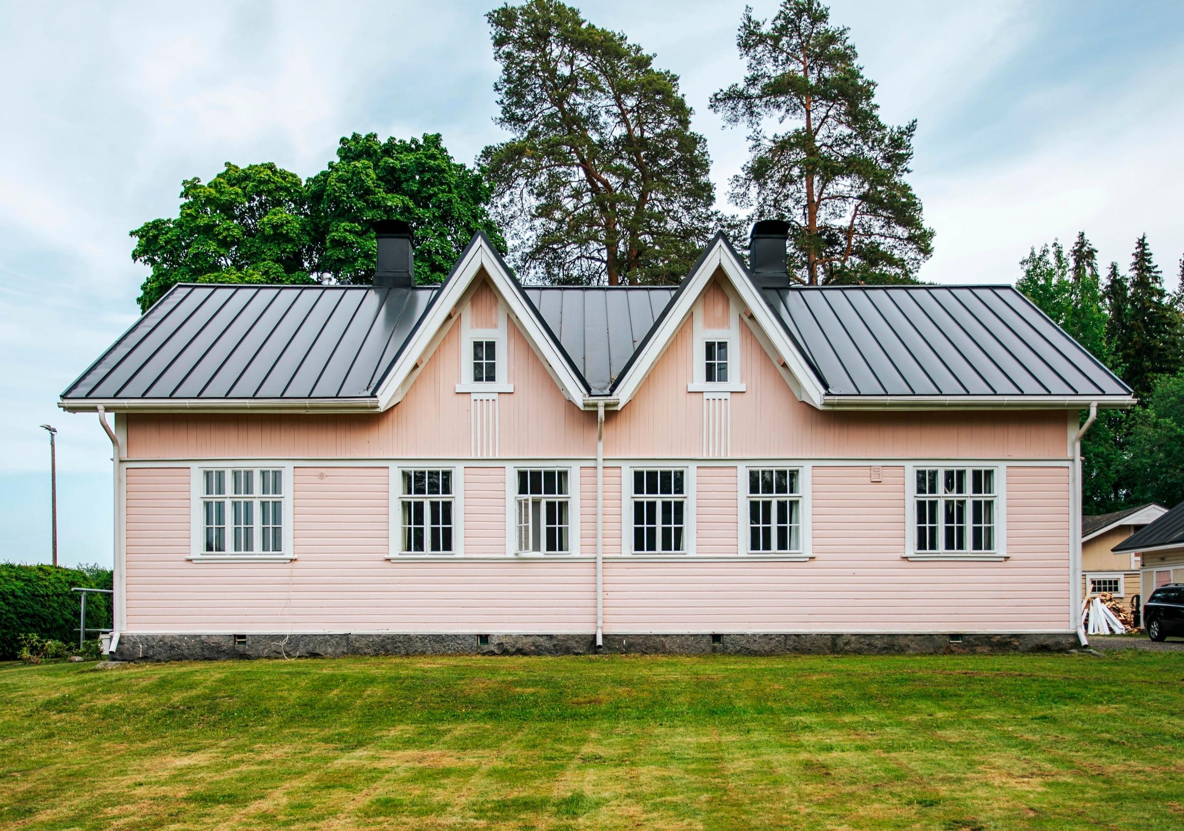Vaaleanpunainen hirsitalo takapihan puolelta