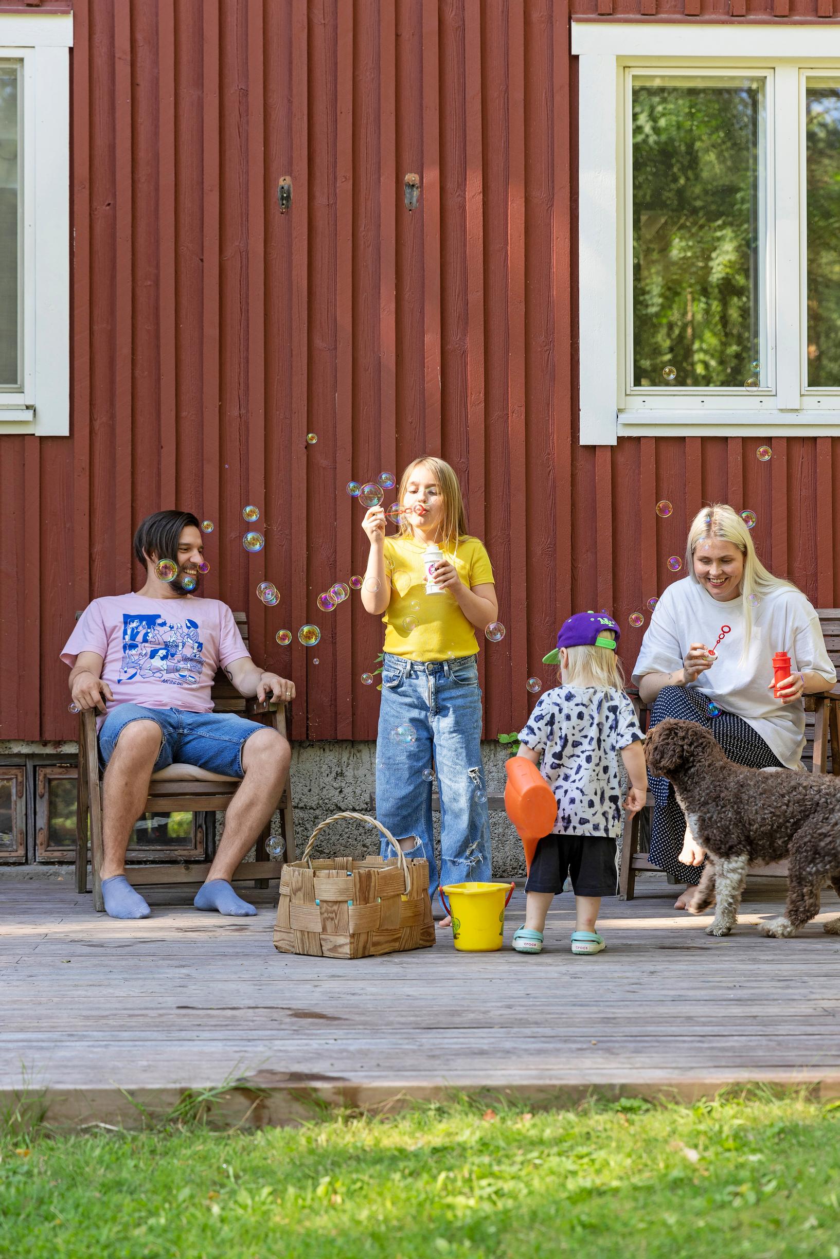 Mikko Virtanen ja Essi Hellén puhaltelevat saippuakuplia lastensa kanssa
