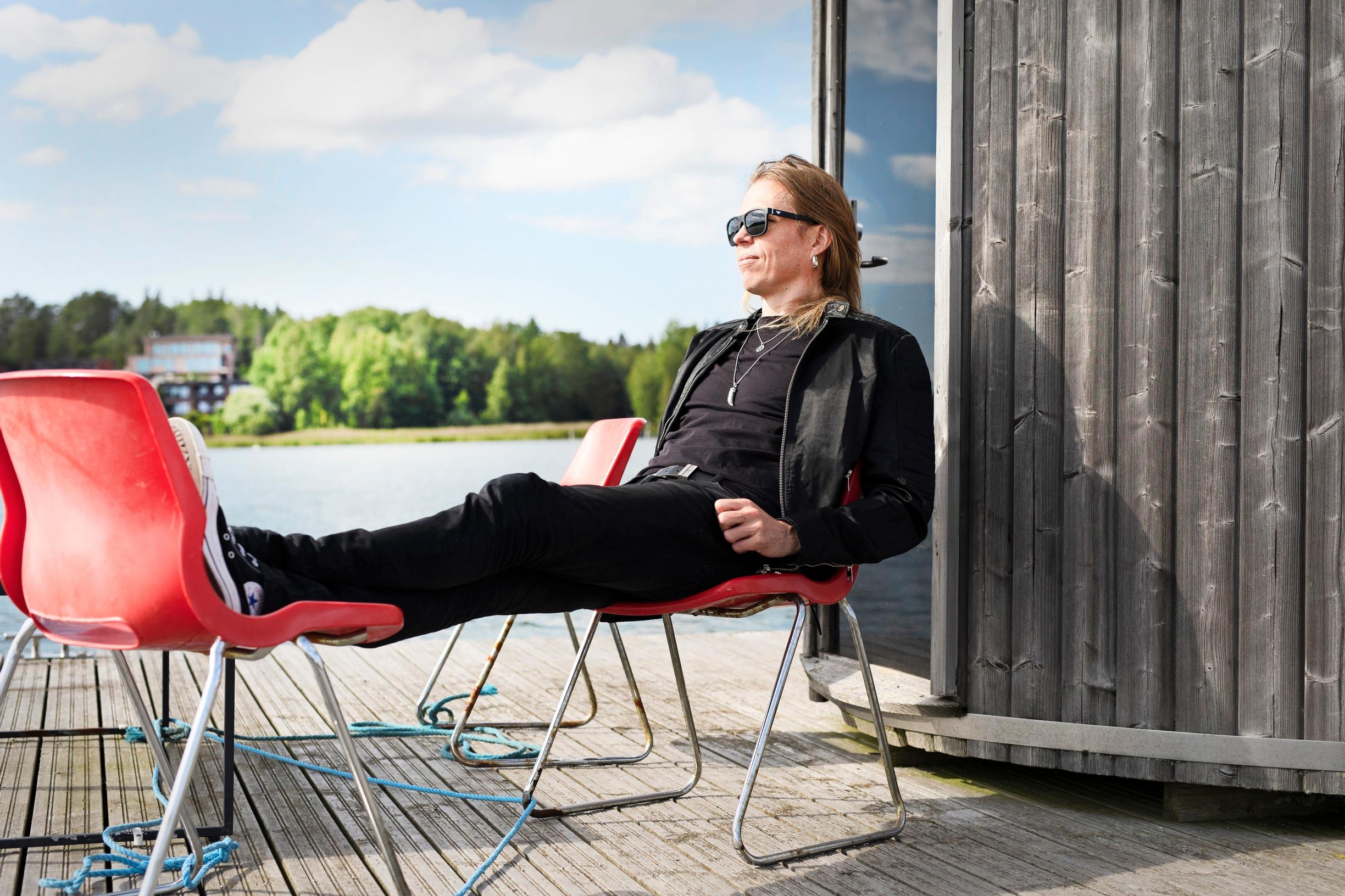 mies istuu tuolilla ja nostaa jalat toiselle tuolille