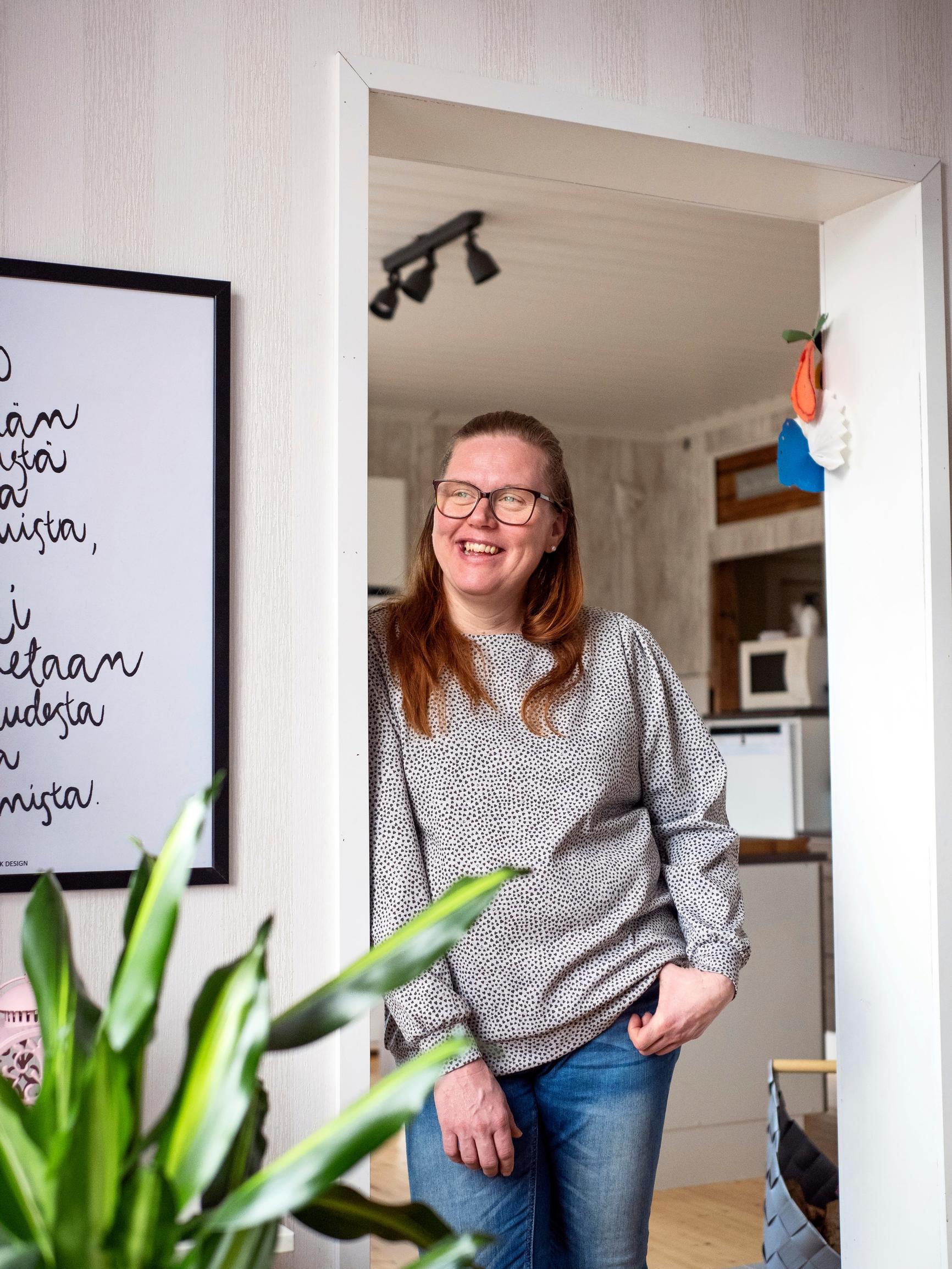 nainen seisoo oviaukossa hymyillen