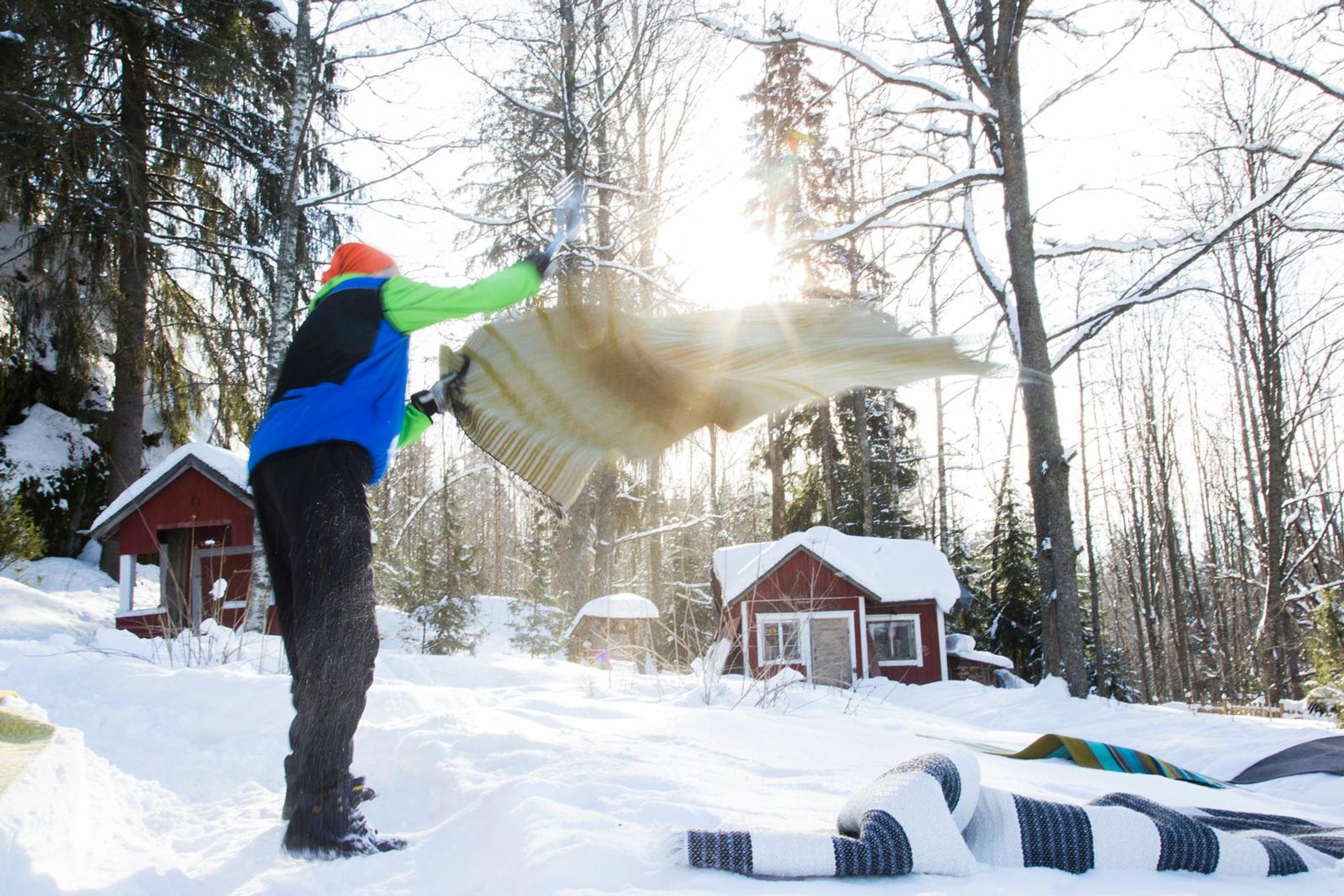 Mies hakkaa mattoja hangessa