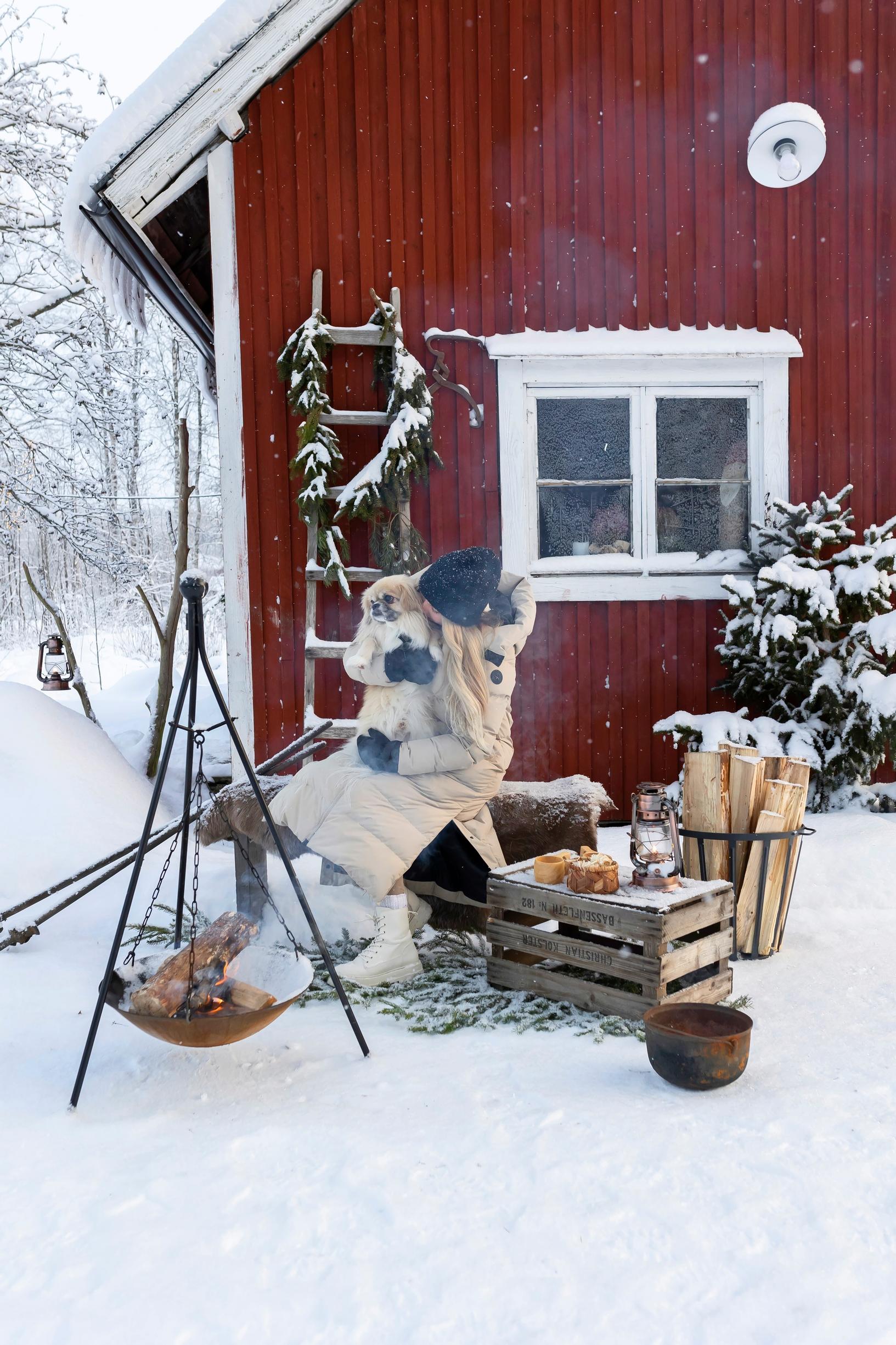 Meeri istuu koiran kanssa nuotion ääressä