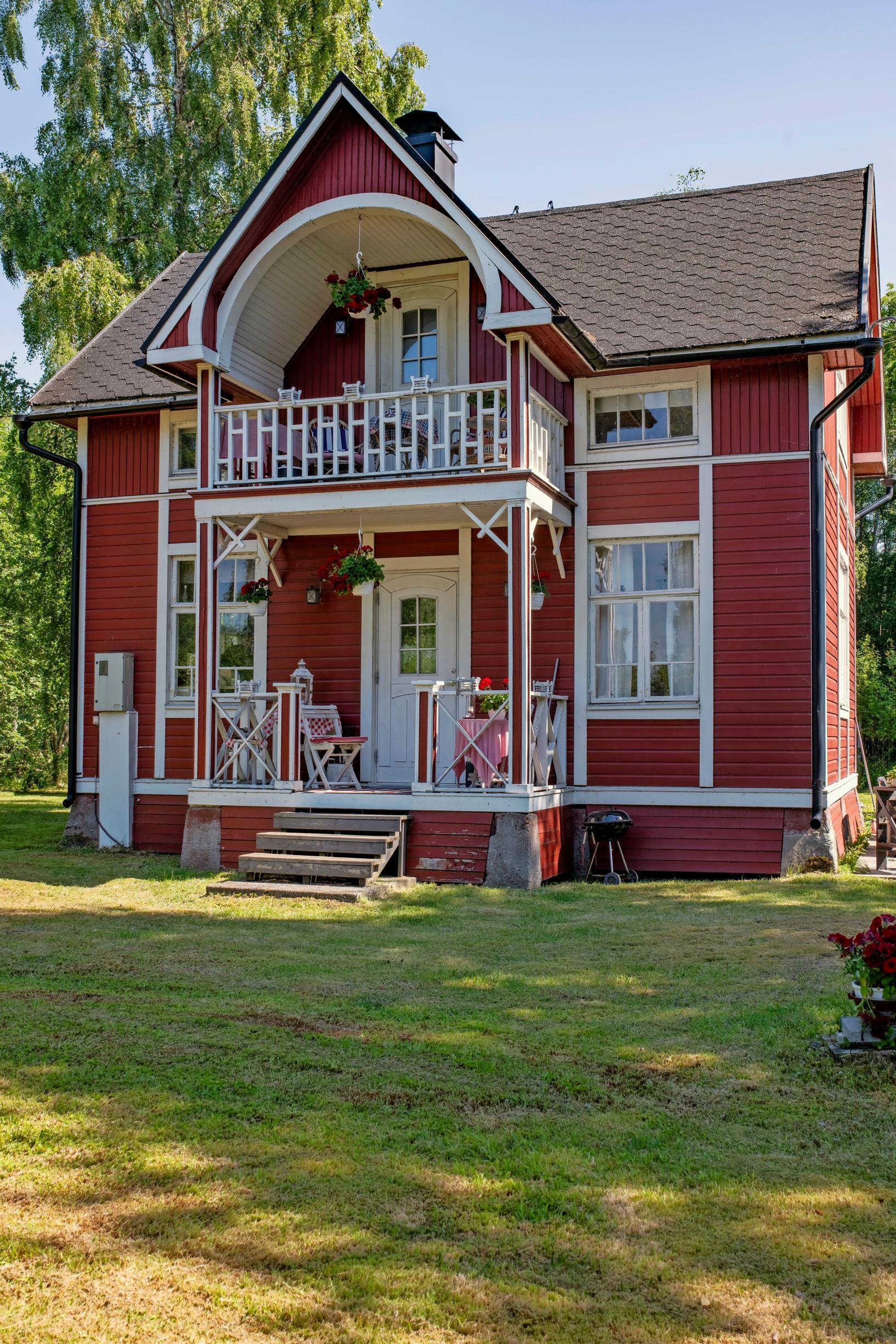 kaksikerroksinen punavalkoinen pitsihuvila ja pihanurmea
