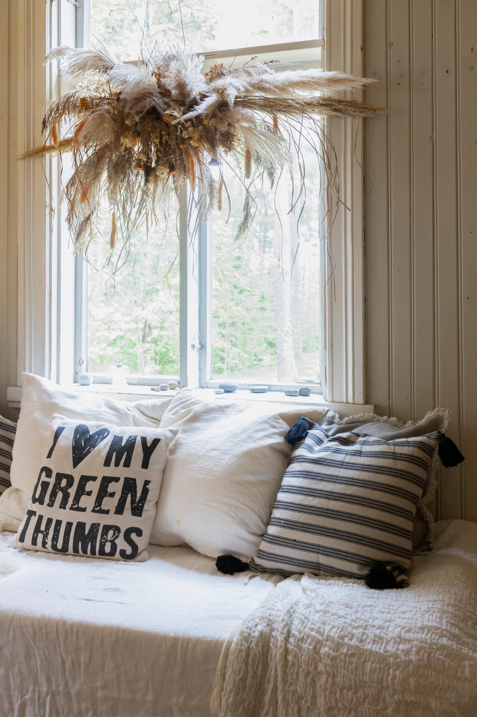 Sohvatyynyjä ikkunan edessä olevalla sohvalla.