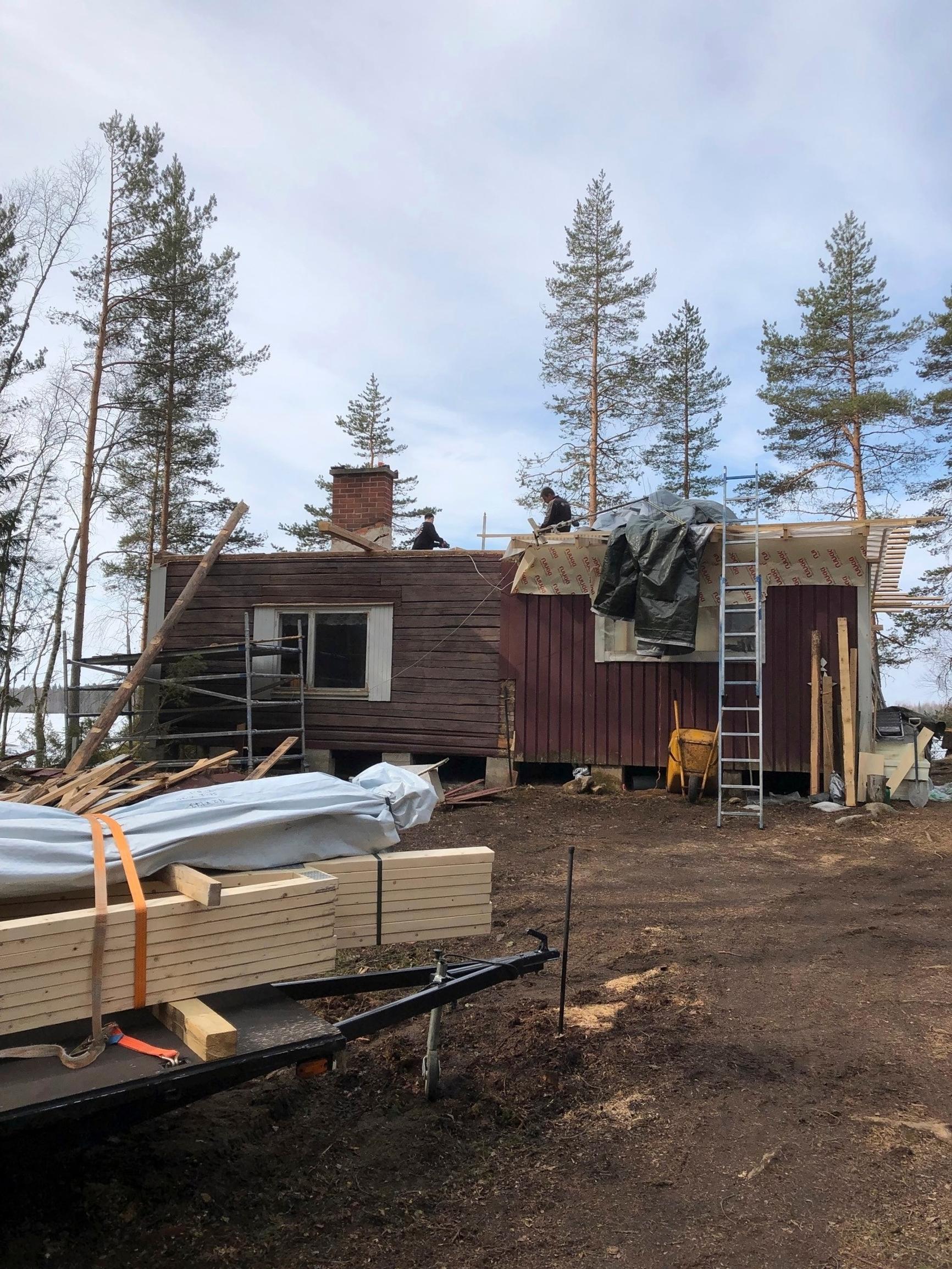 remontissa oleva revitty hirsimökki ja uusia lautoja, metsää