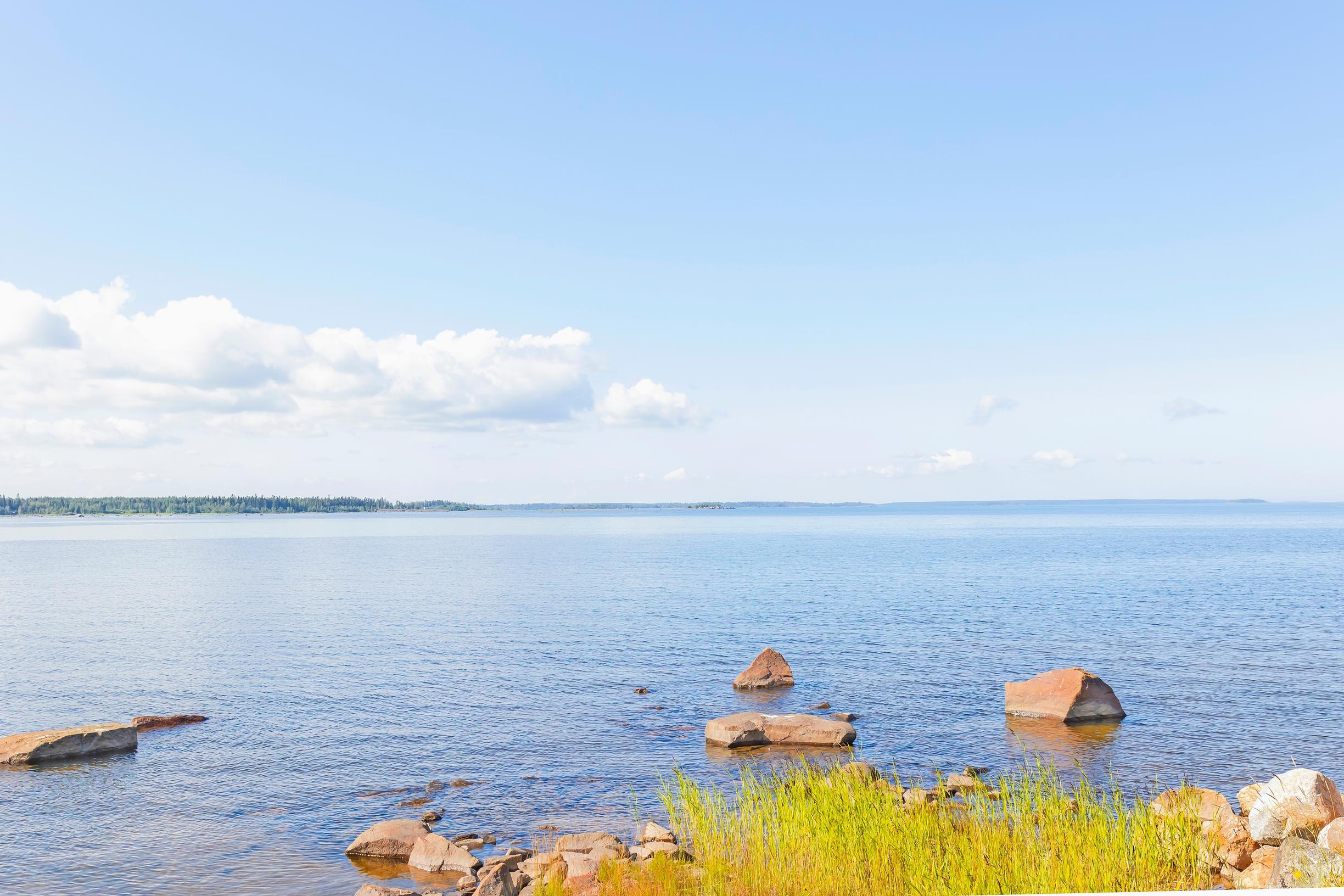 merimaisema, pilviä ja rannan lähellä kiviä ja heinää