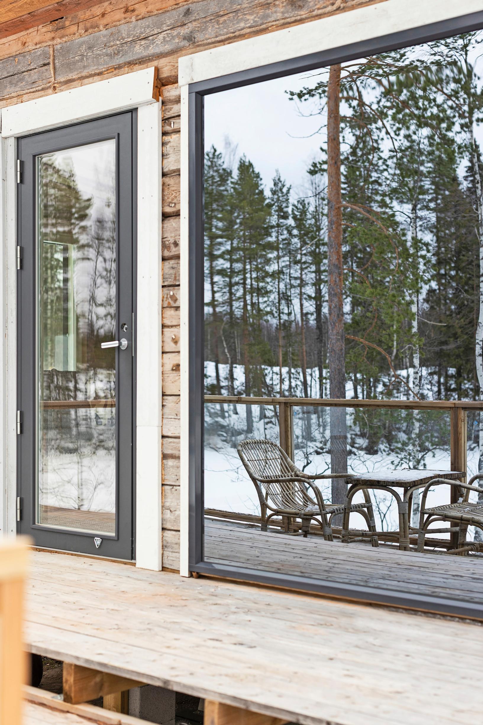 ikkunoista peilautuva mökin terassi, jolla pöytäryhmä