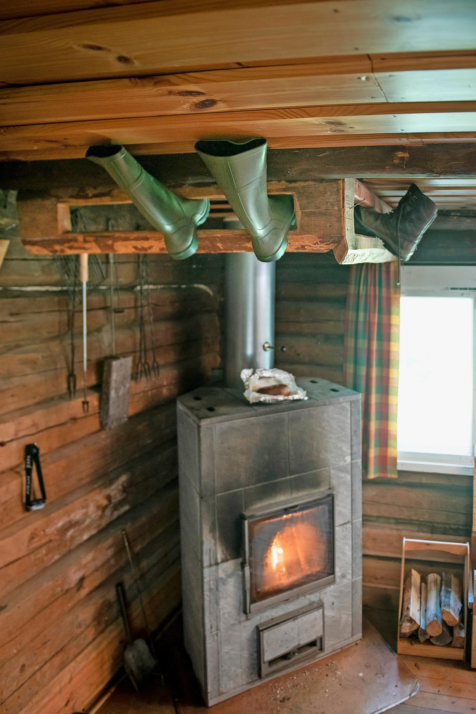Saappaat kuivuvat telineessä katossa tulisijan yllä