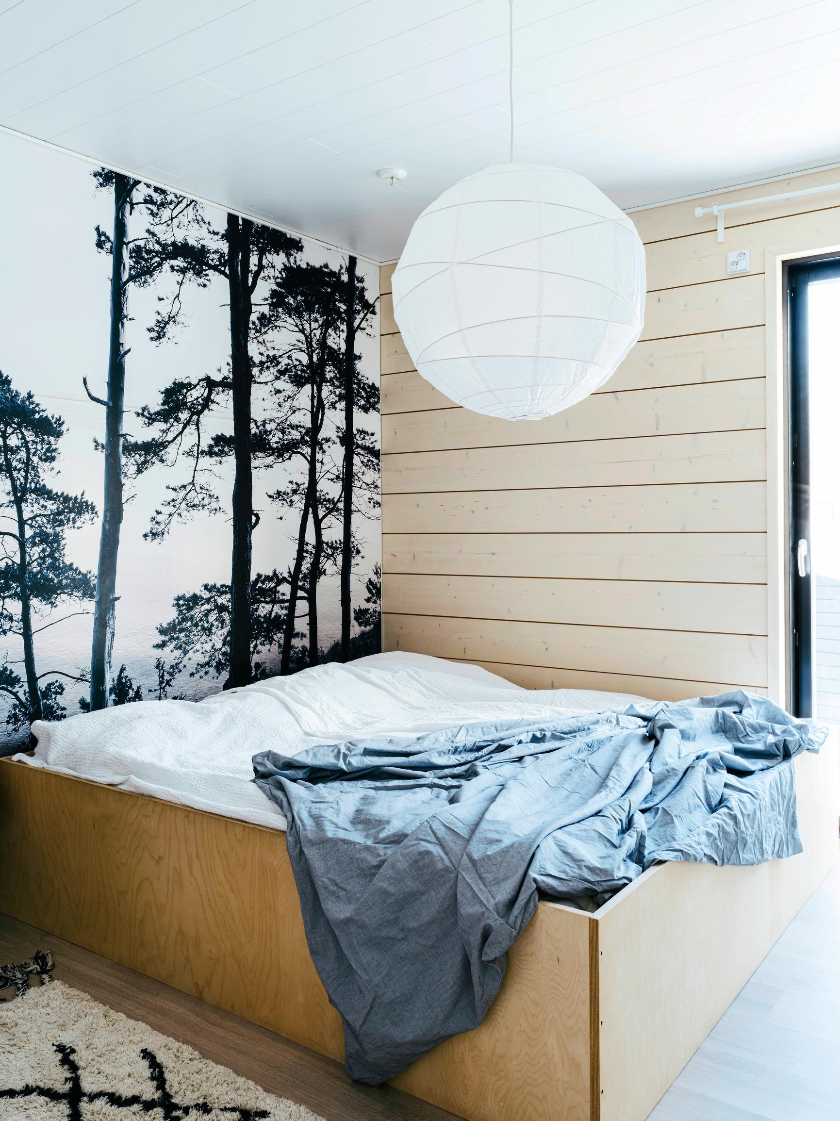 Vanerilaitainen parisänky ja näyttävä metsätapetti makuuhuoneessa