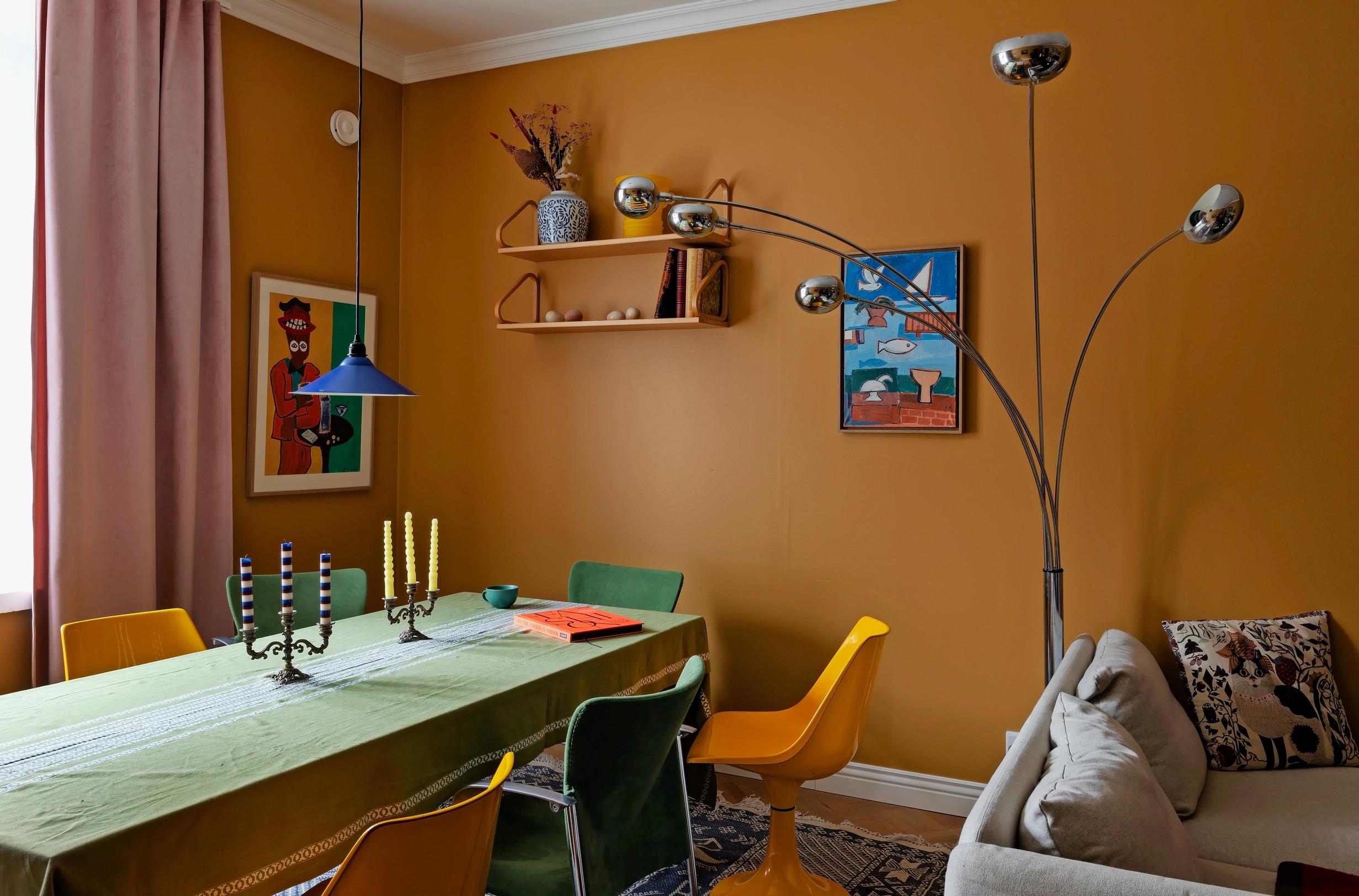Kuva olohuoneen ruokailuryhmästä, jossa monenlaisia vintage-tuoleja. 