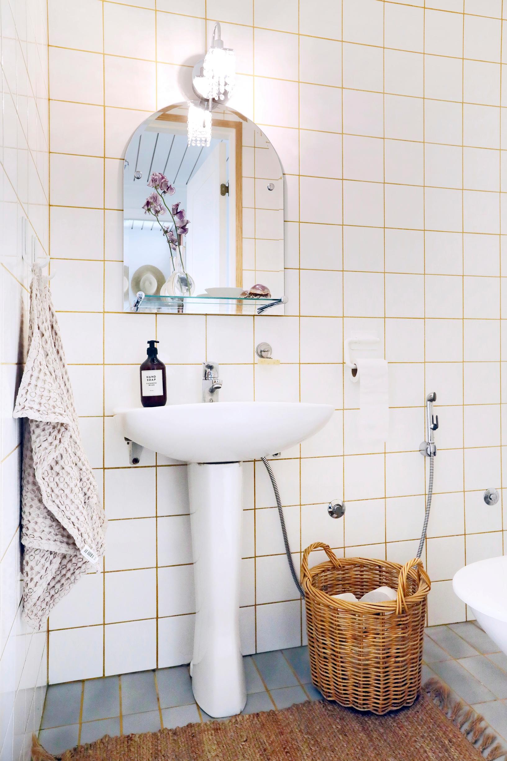 Kuva wc:stä, jossa valkoinen laatoitus ja beiget saumat.
