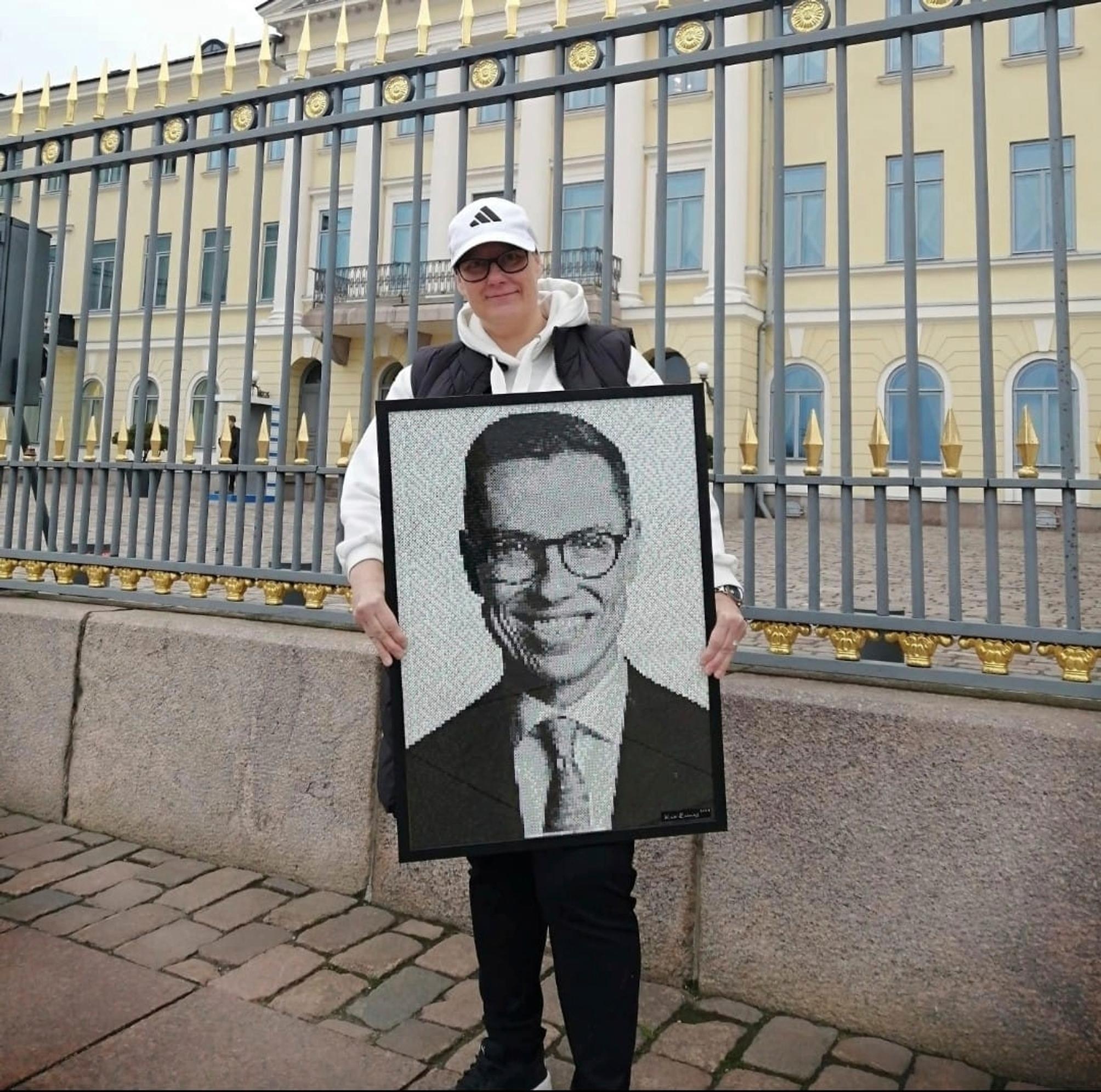 Kati presidentinlinnan edustalla, kädessä Alexander Stubbia esittävä taulu.