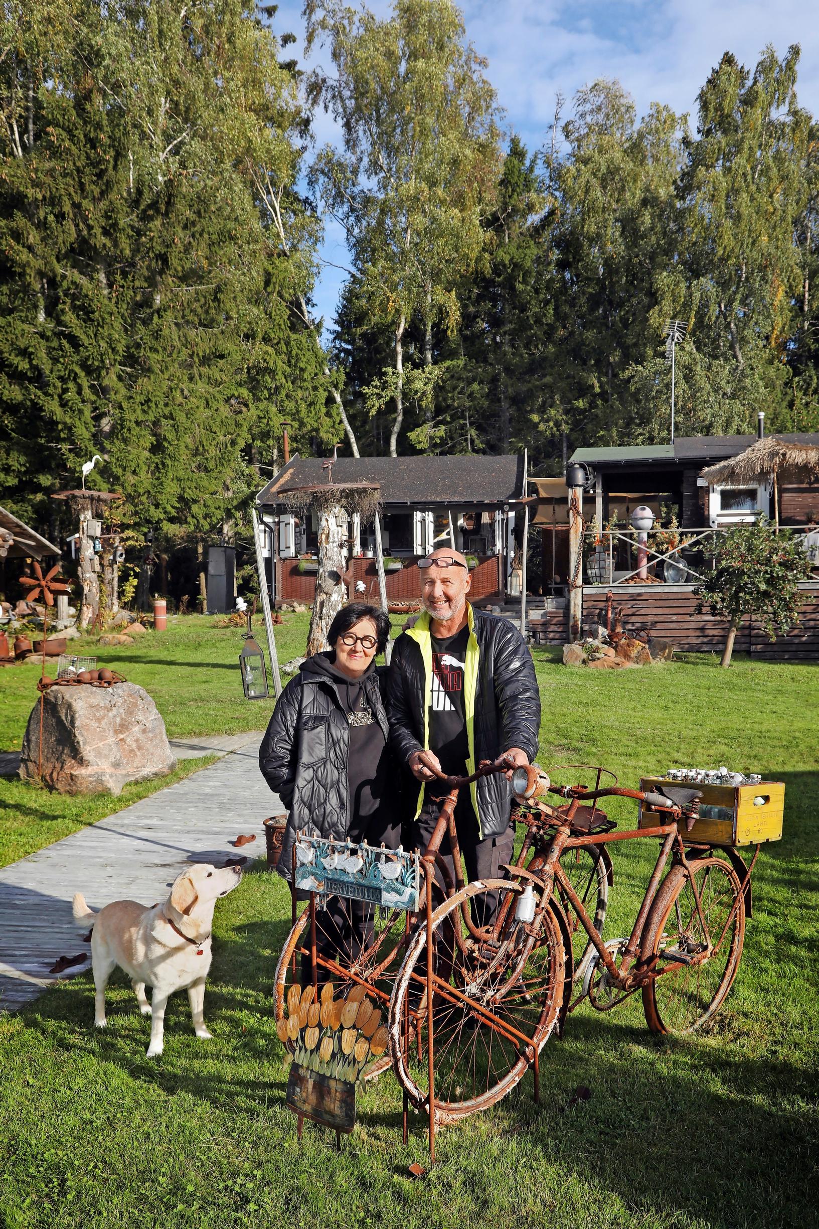 Sanna ja Markku Parkkari ruosteisten polkupyörien vieressä ja koira