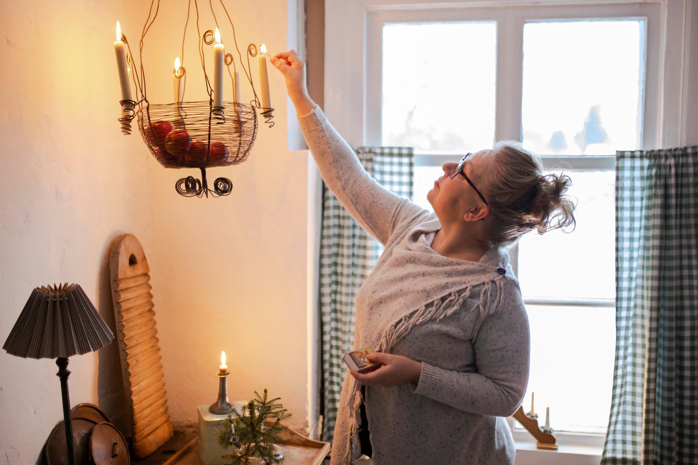 Johanna sytyttää kynttilöitä roikkuvaan kynttelikköön