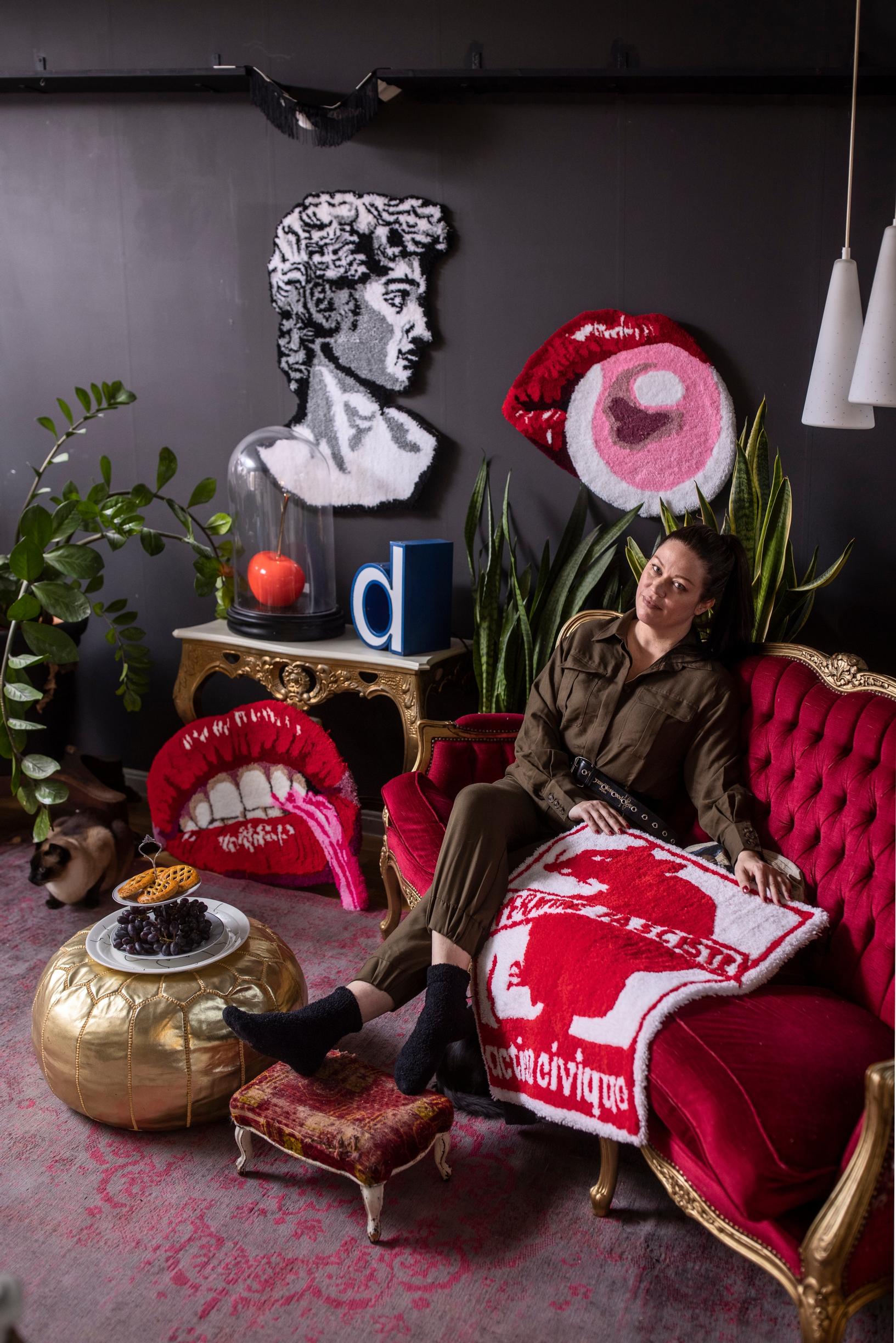 Heidi Linsén sohvalla ympärillään tuftaamiaan ryijyjä