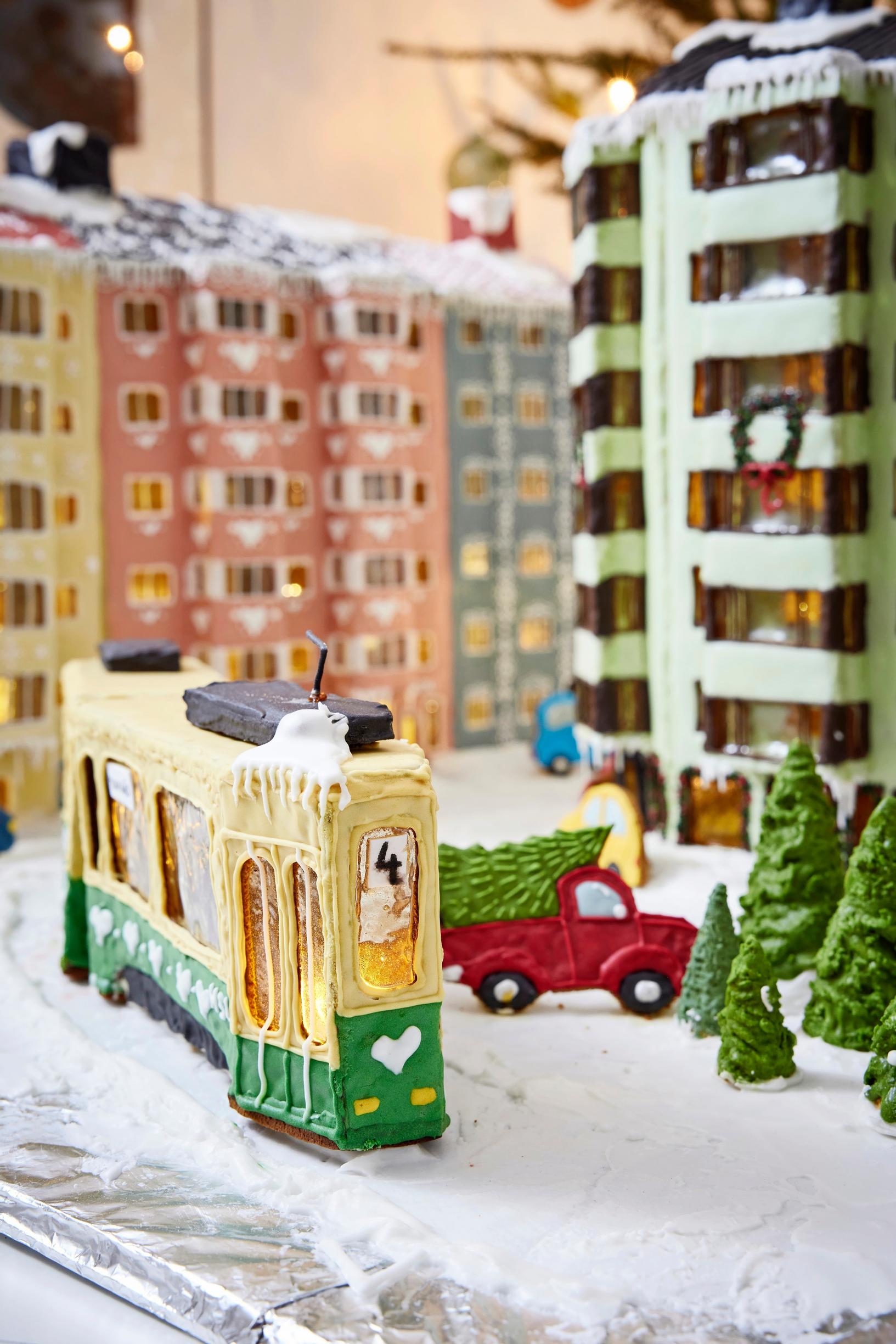 Piparkakkukortteli, jossa vihreällä ja vaaleanpunaisella pikeerillä päällystetty 50-luvun kerrostalo erkkereineen. Keskellä ratikka.