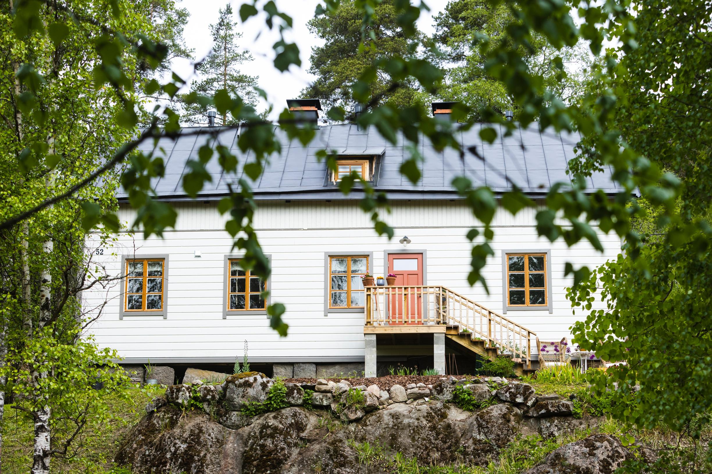 Remontoitu valkoinen talo. Edessä portaikko ja sisäänkäynti.