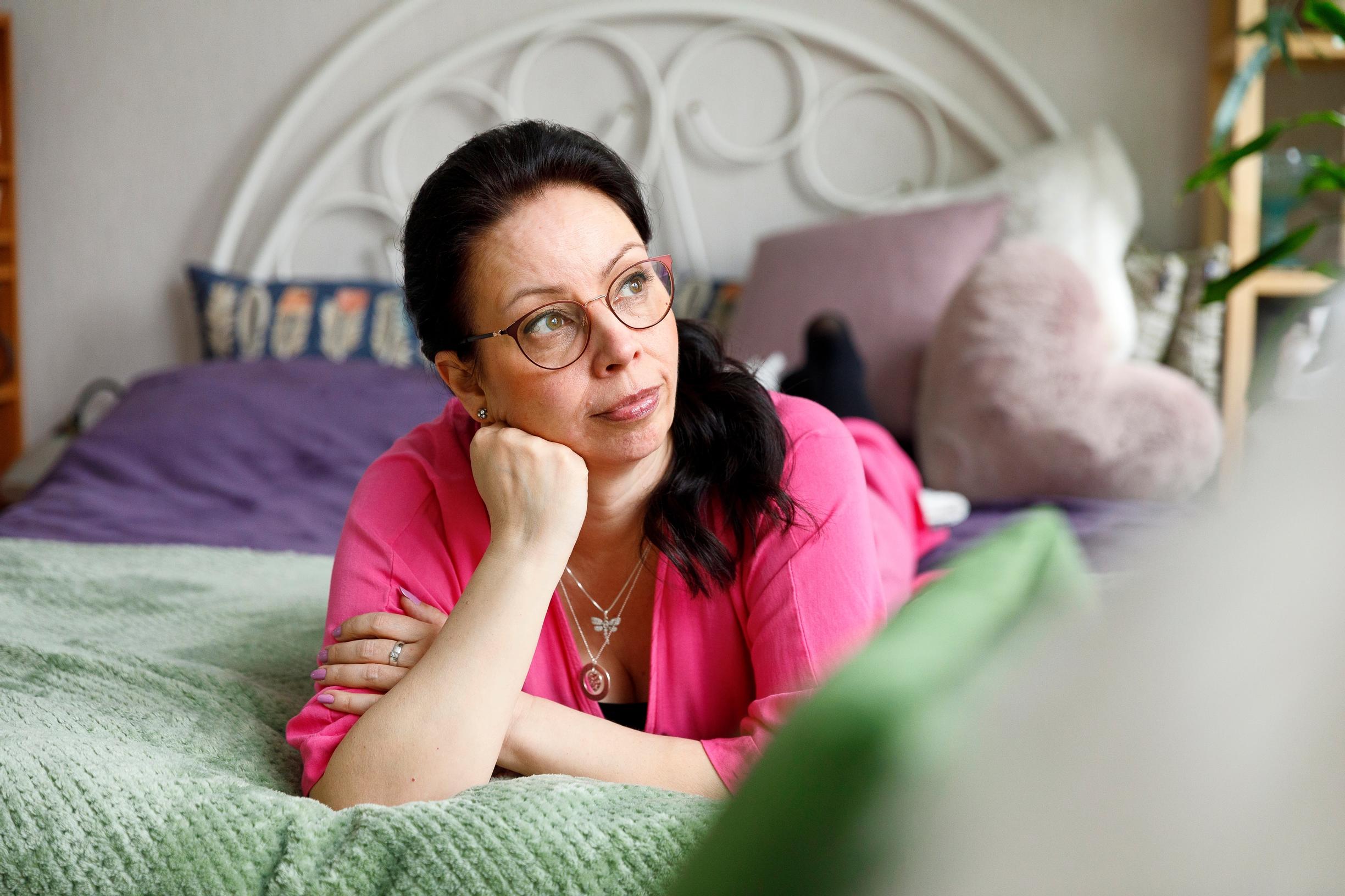 nainen nojaa käteensä sängyn päällä