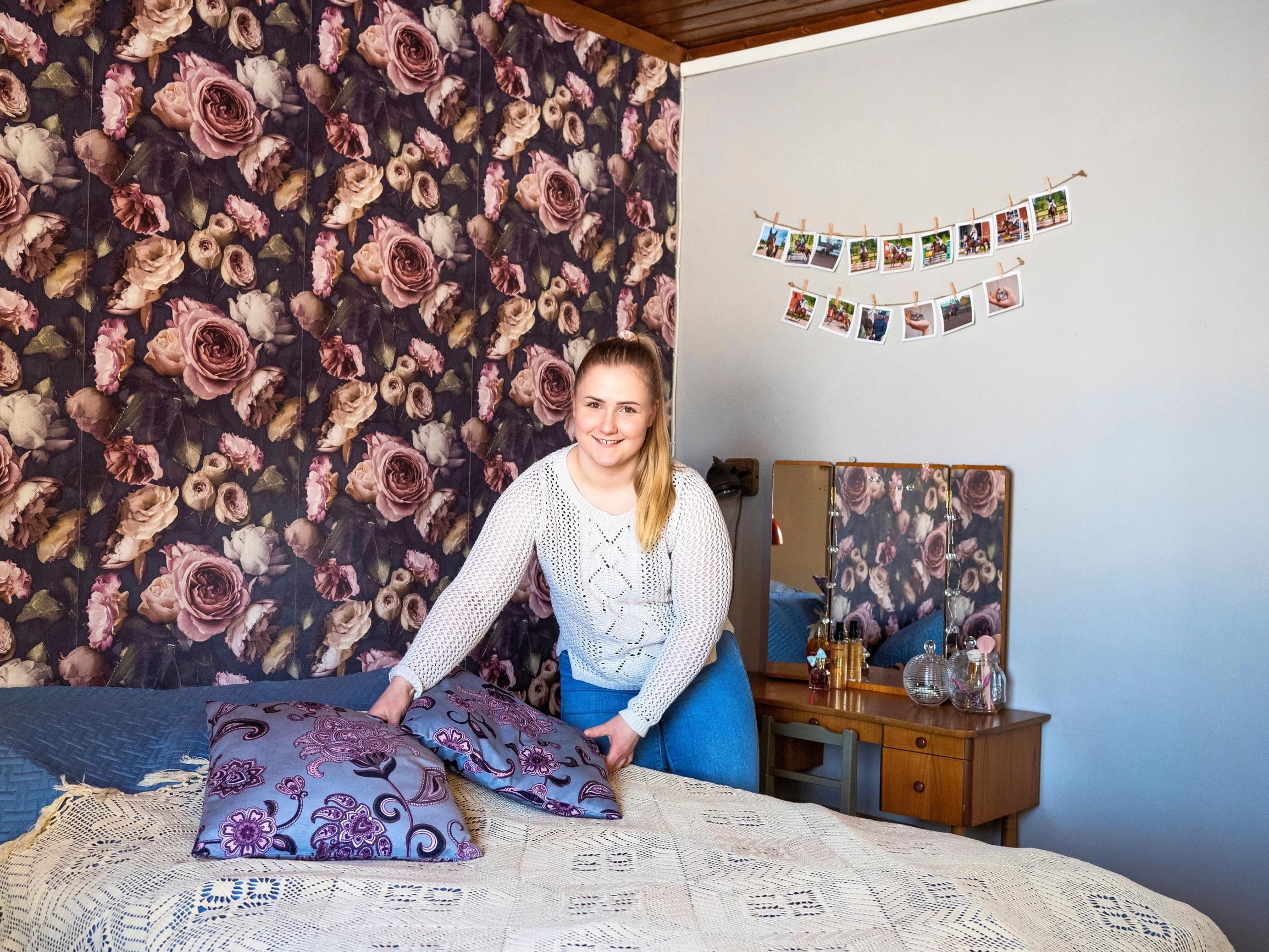 nainen asettelee koristetyynyjä sängylle