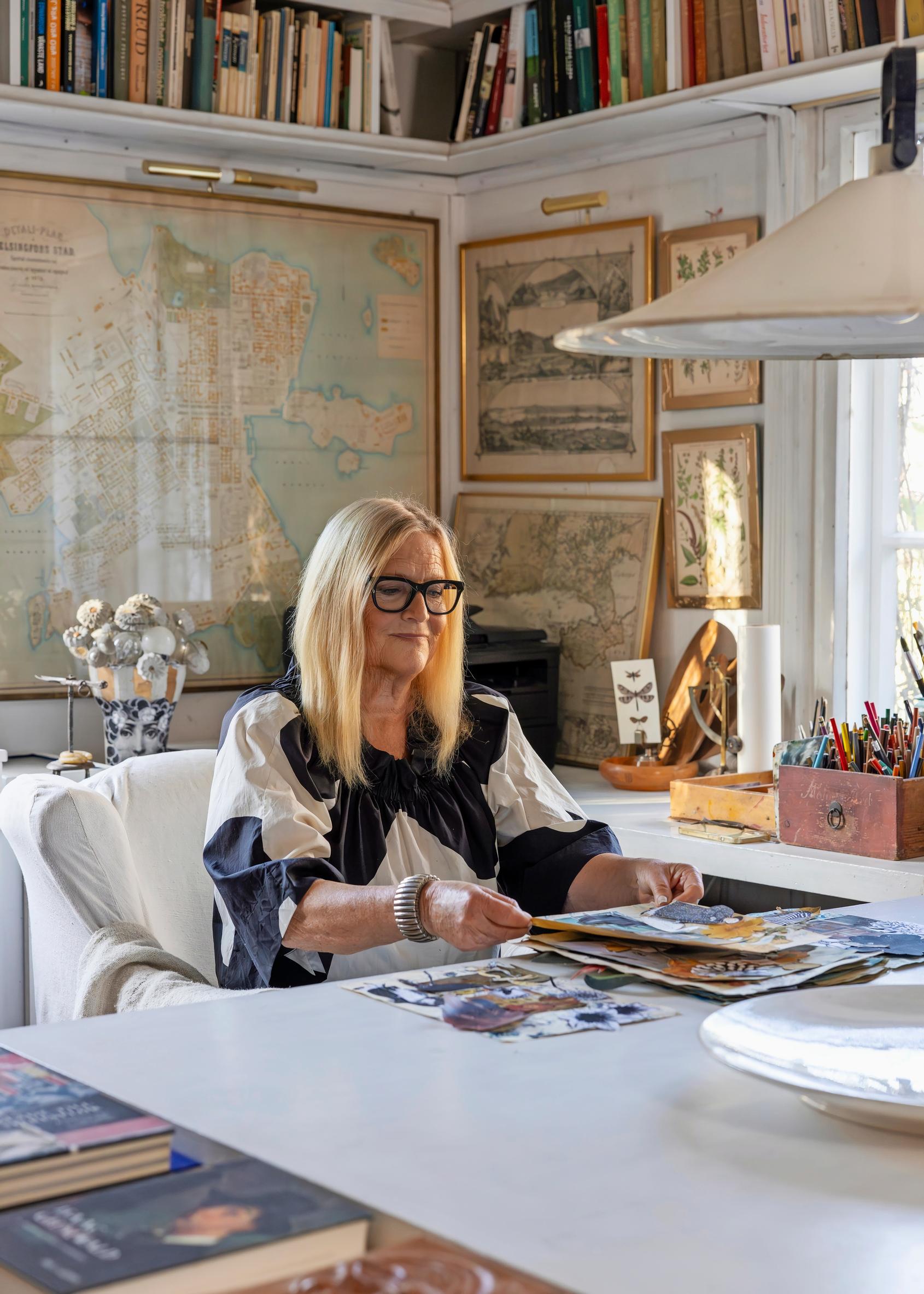 Kerstin Enbom istuu pöydän ääressä kirjastossaan.