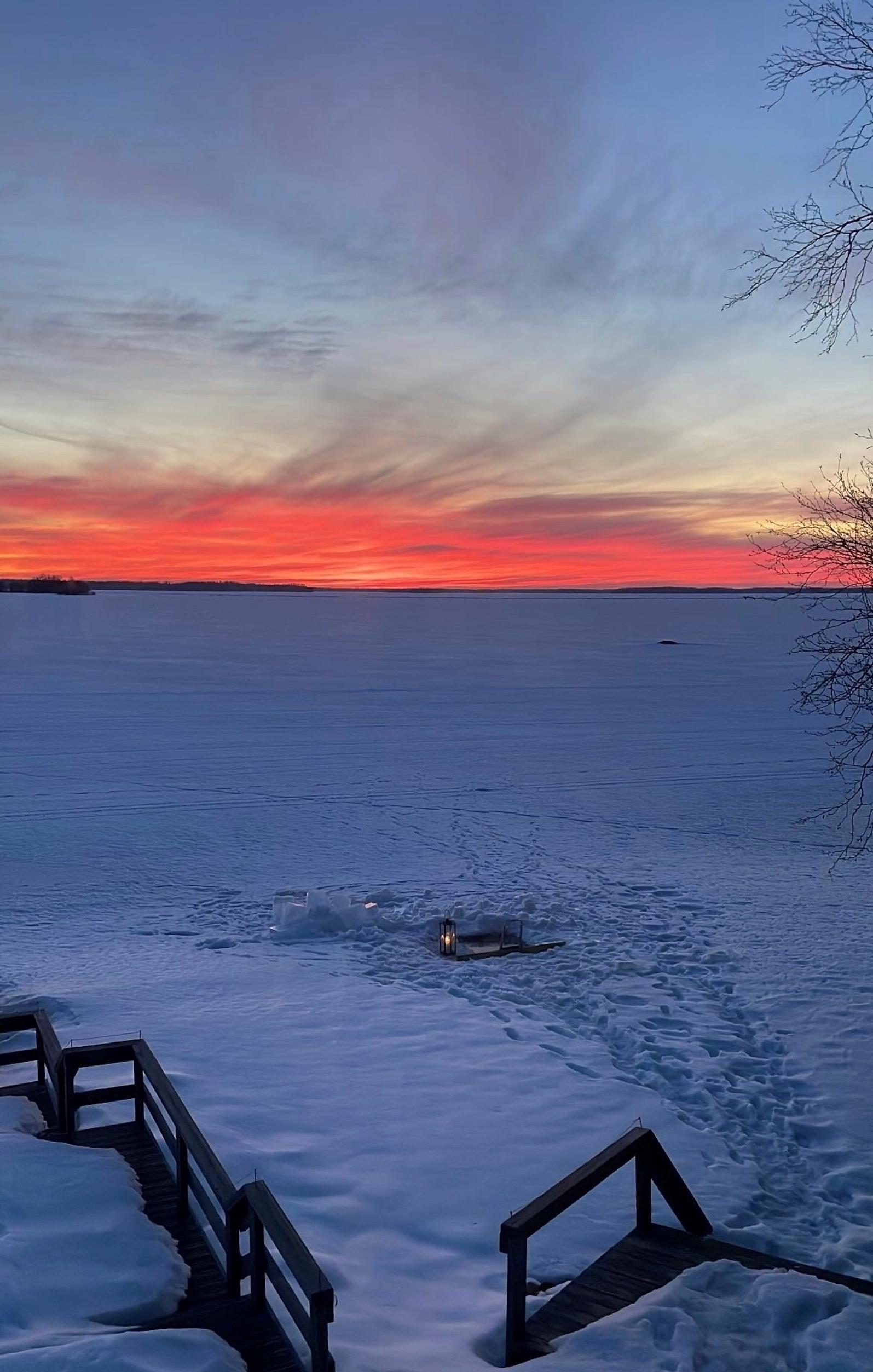 auringonlasku talvisella järvellä