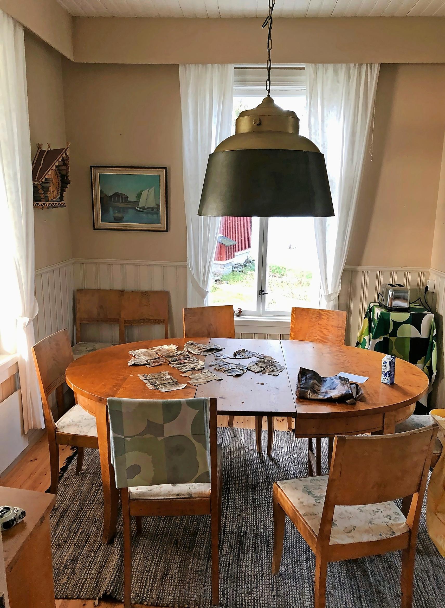 iso kattovalaisin pyöreän pöydän päällä, puutuolit, ikkuna ja taulu
