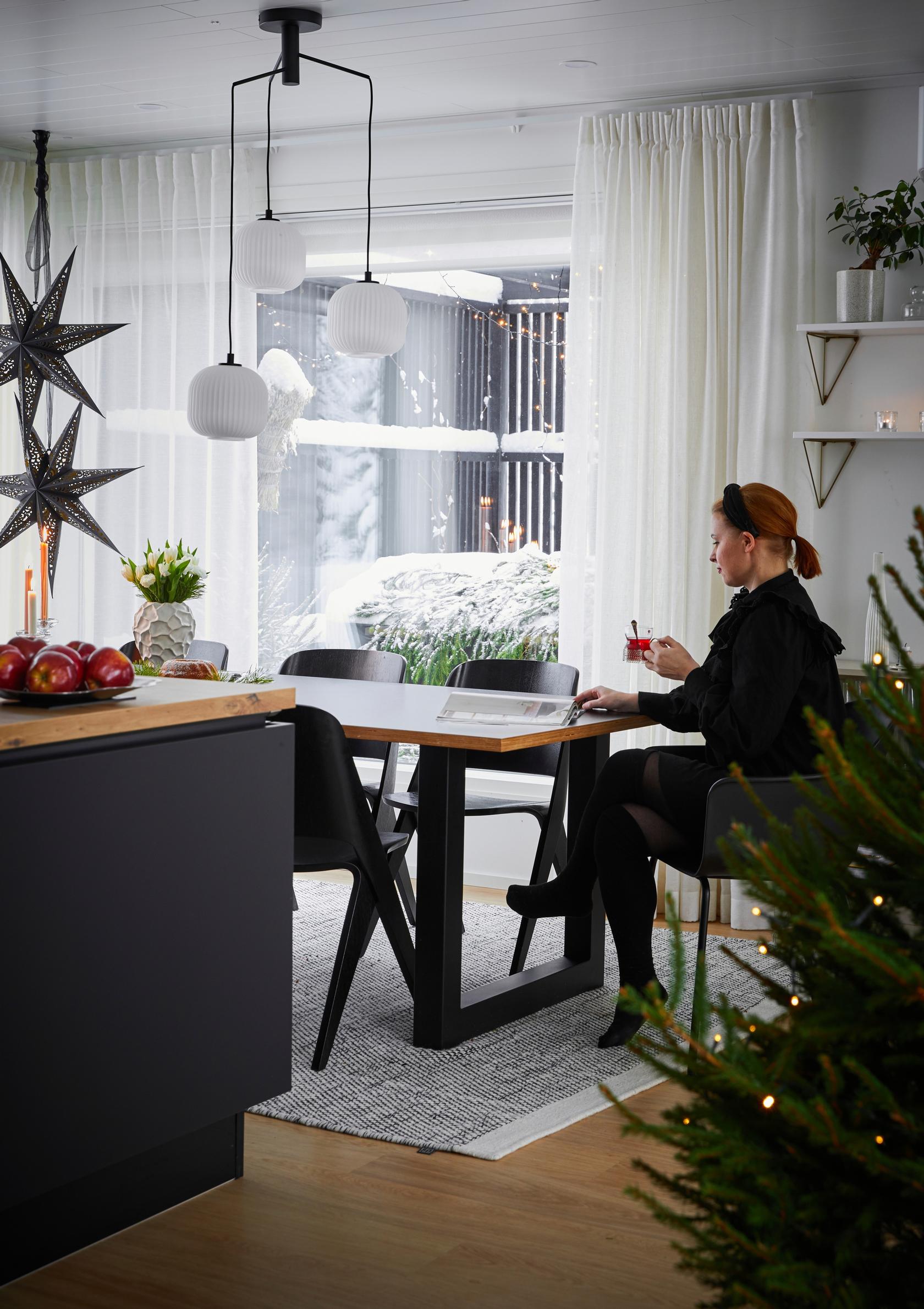 Julia istuu pöydän ääressä, joulukuusi ja joulutähtiä