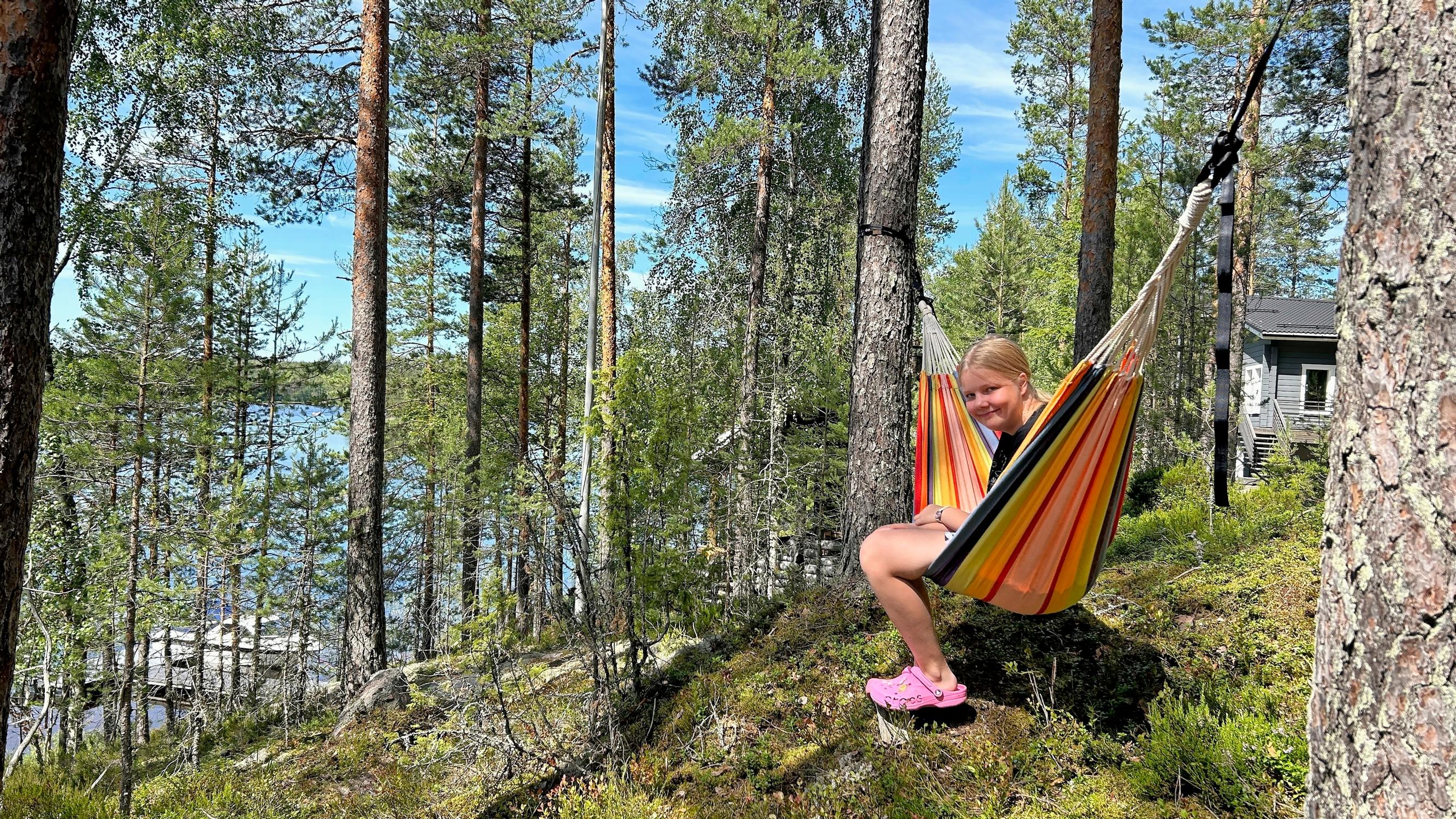 Alma Kaartinen istuu riippumatossa mökkirinteen metsässä