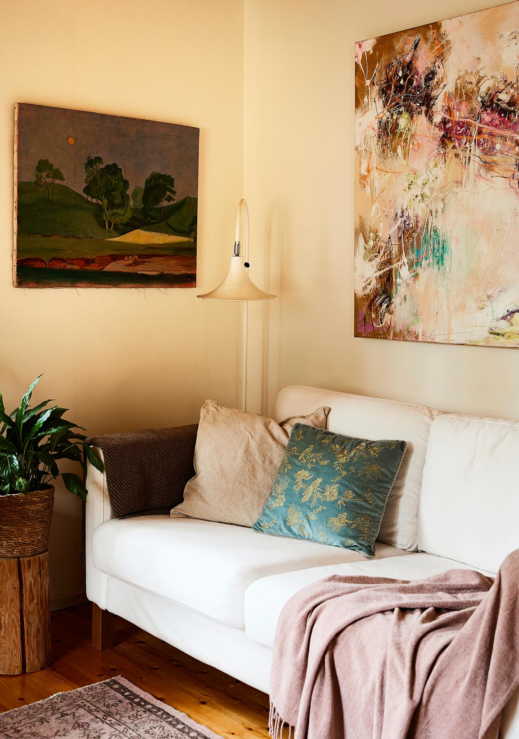 Ria Bäckströmin ja Risto Kuntsin maalaukset sohvan yläpuolella