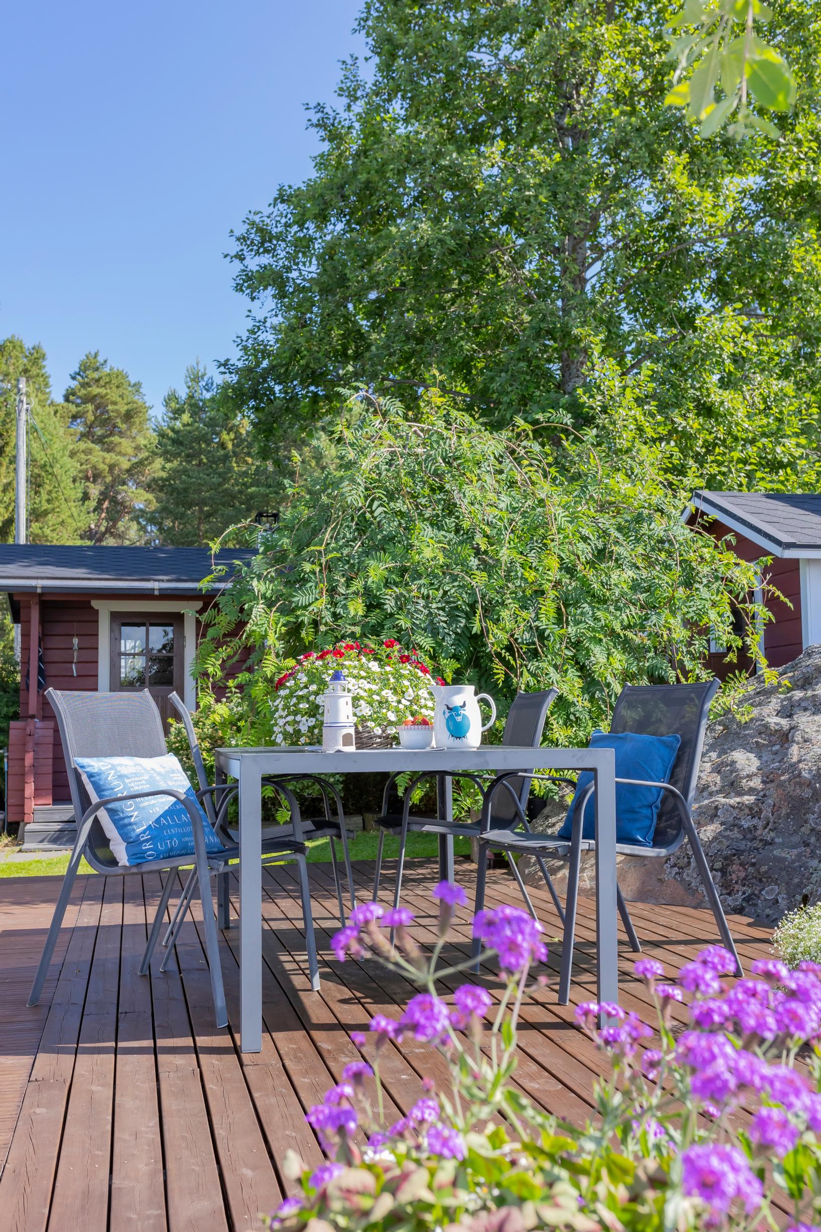 pöytäryhmä terassilla, rakennus ja kesäkukkia