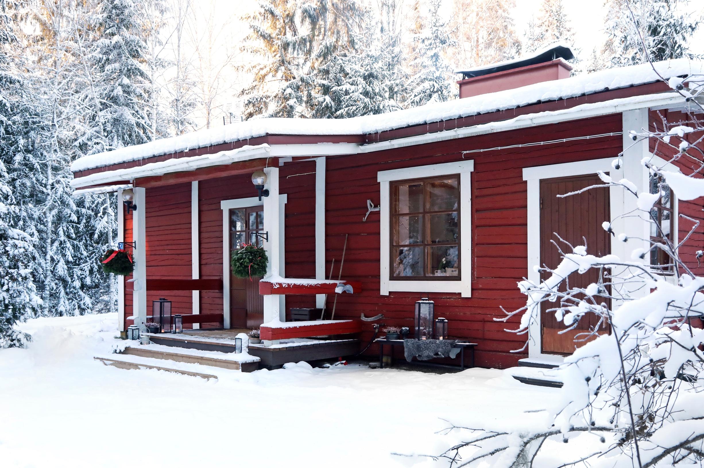 Ulla Parviaisen punainen hirsimökki Pusulassa Lohjalla, taustalla lumista metsää